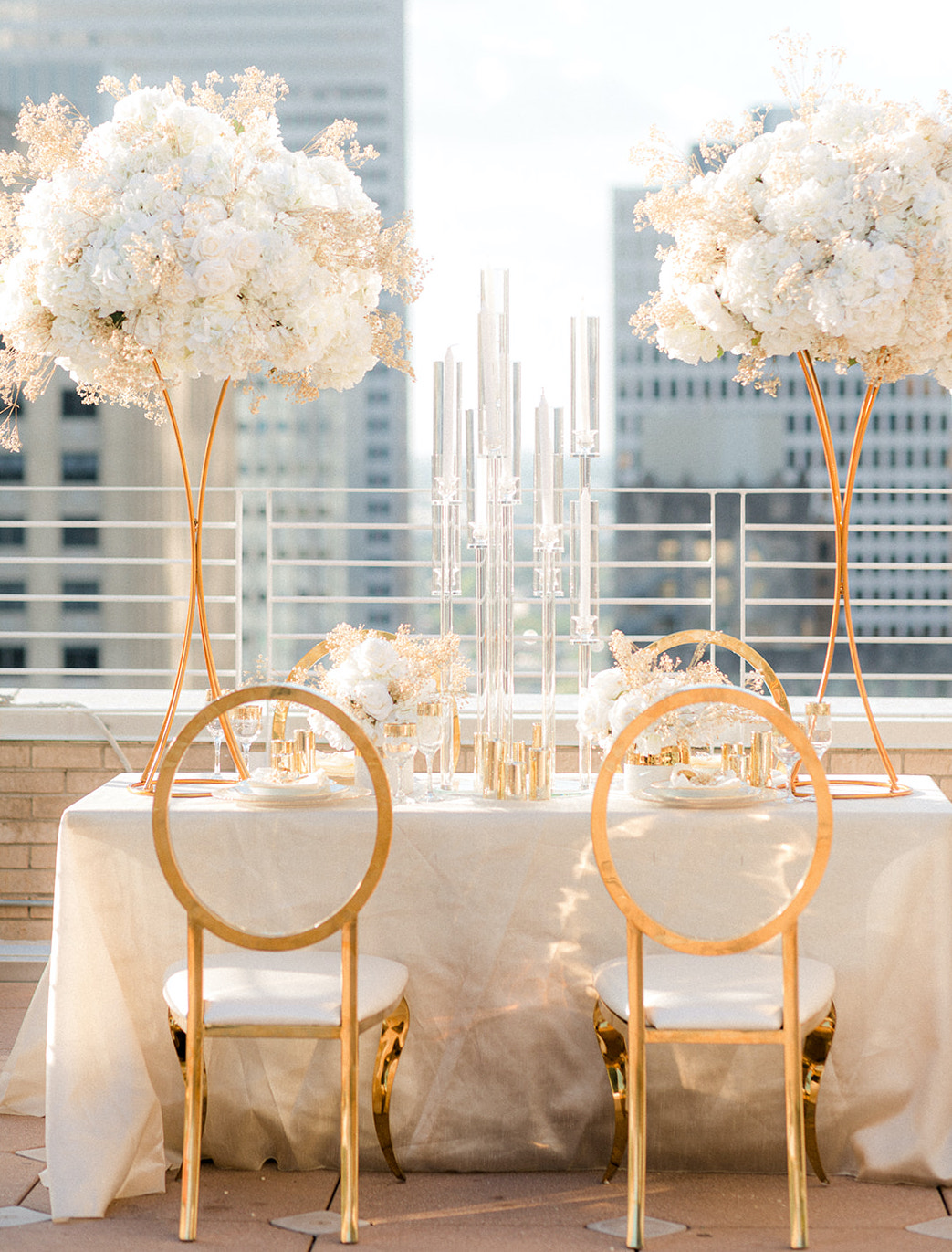 The sunlight reflects off of the gold chairs and dinner table used for the ethereal rooftop wedding styled shoot.