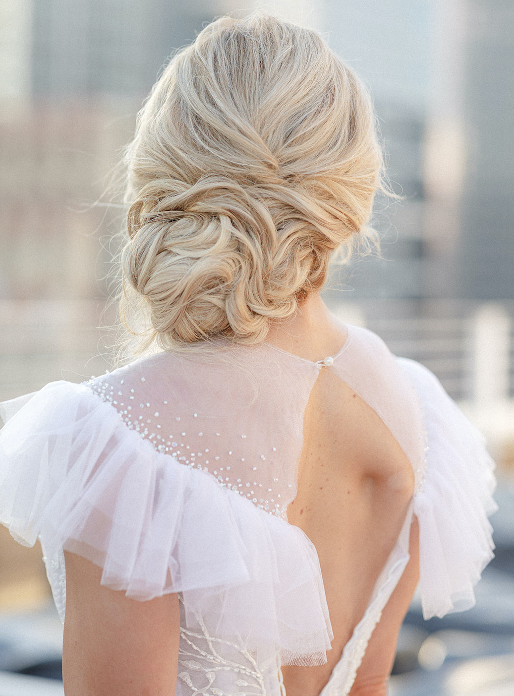 The bride's hair is in a low loose bun that is positioned to the side of her shoulder.