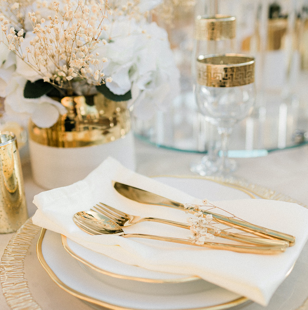 Gold dinnerware and flower arrangements decorate the dinnertable.