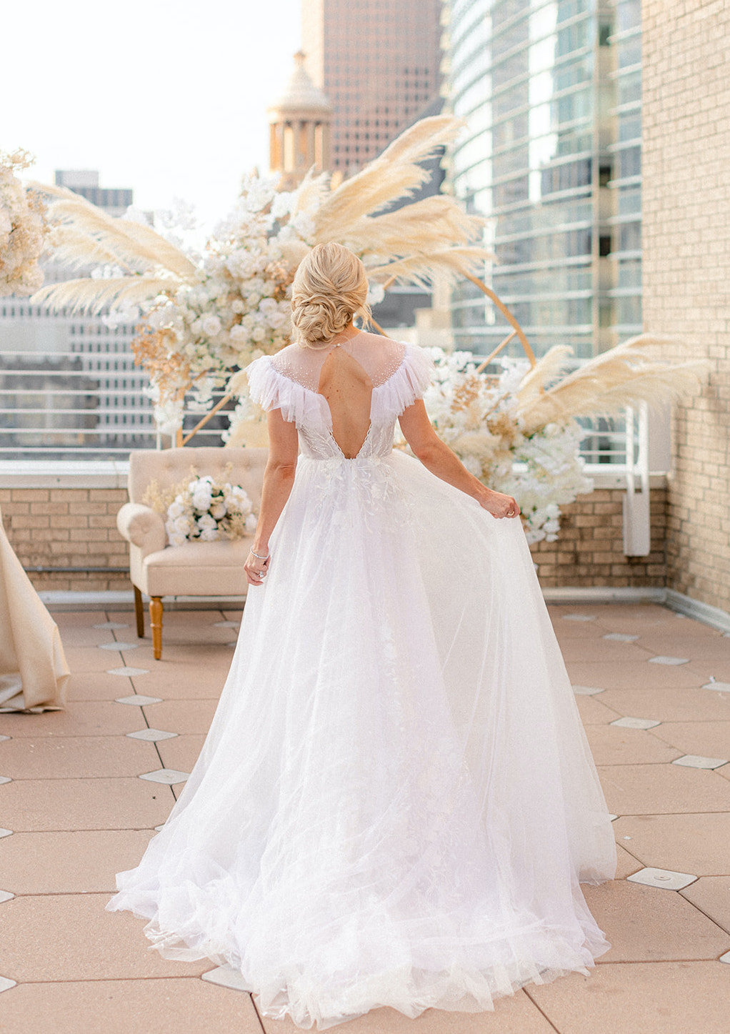 The bride sways with her back to the camera, revealing her backless gown and the embellishments in the fabric.
