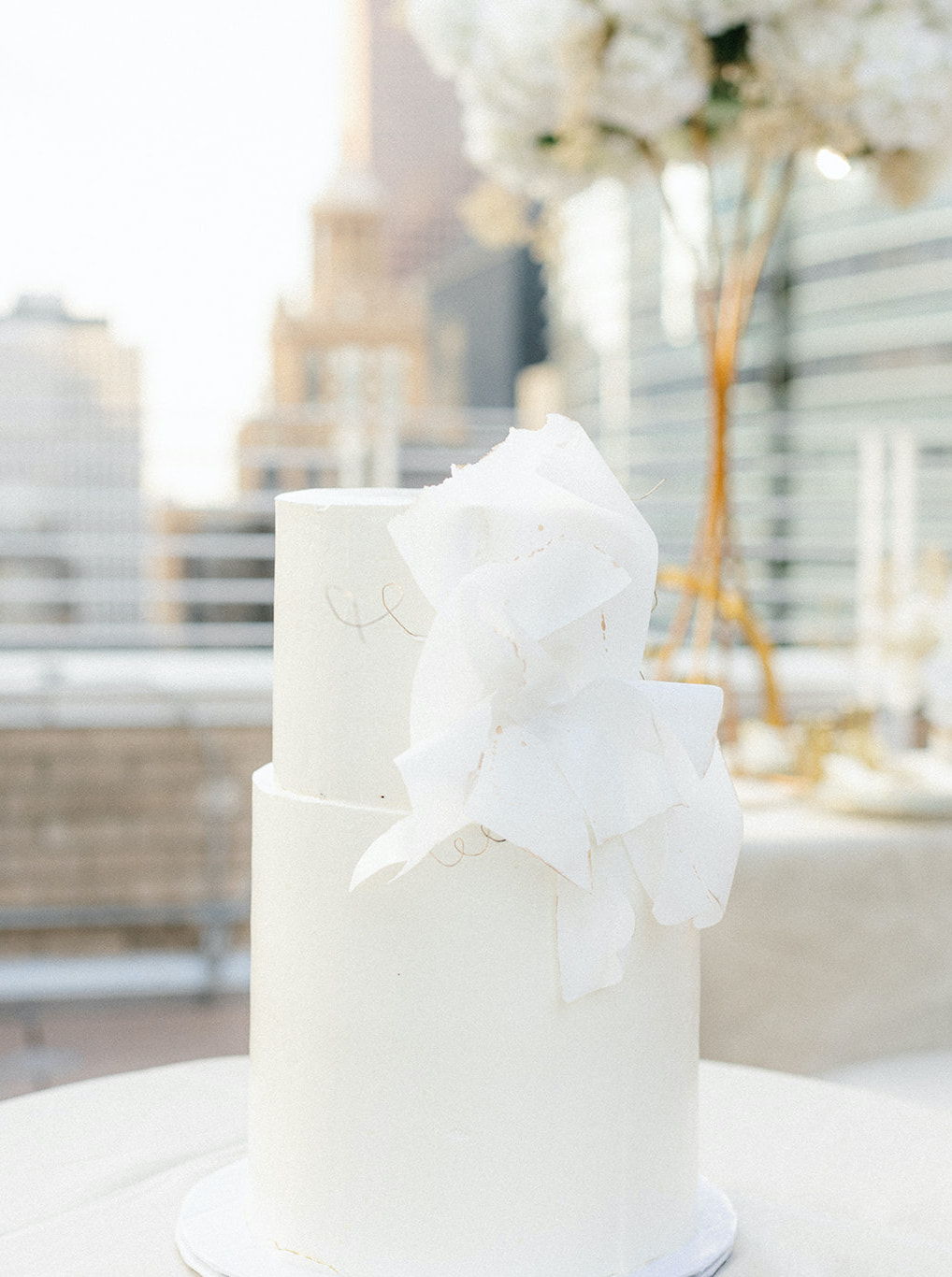 The wedding cake is pure white with a ruffled design on the side.