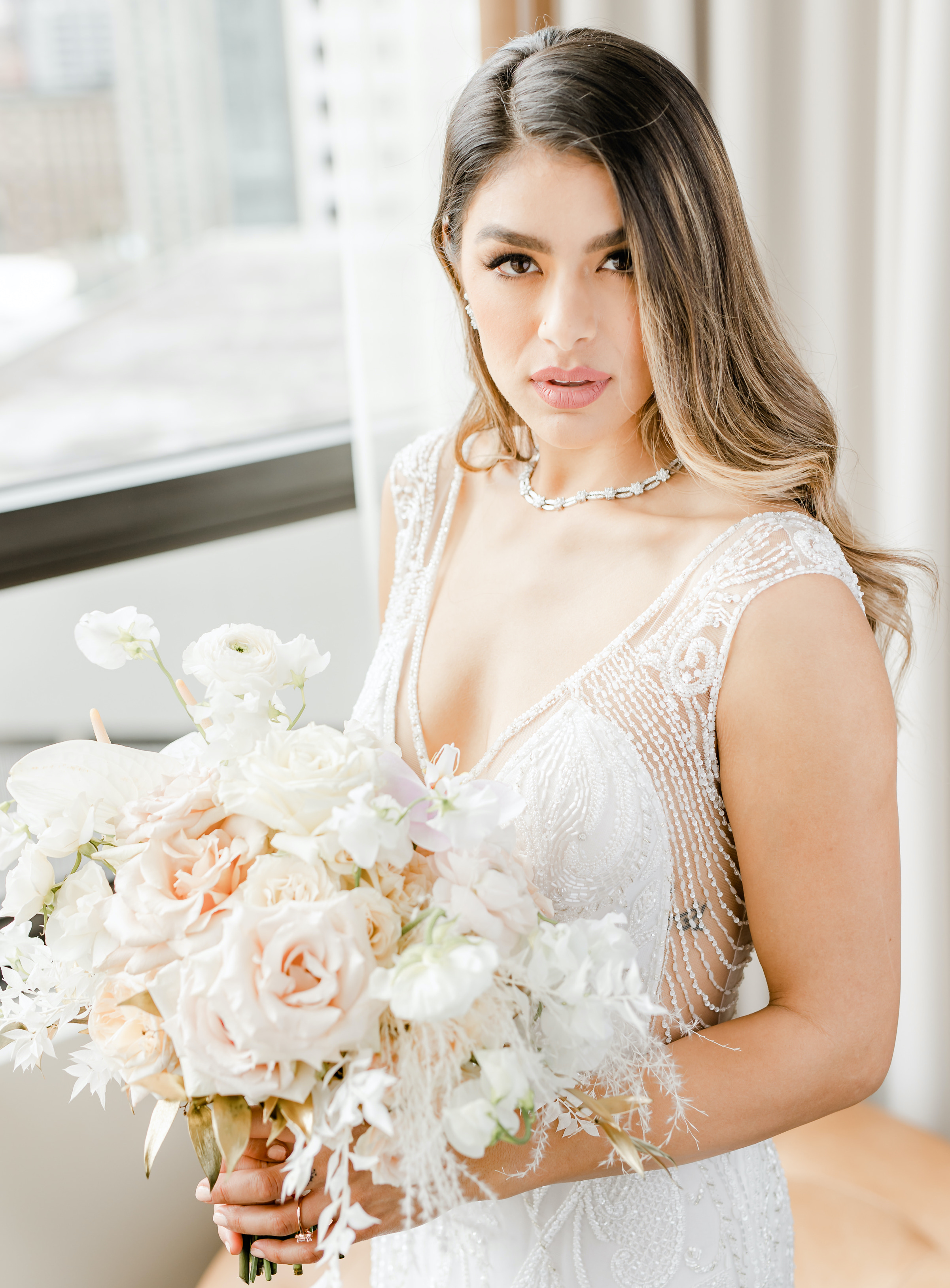 A bride looks at the camera holding a bridal bouquet at The Four Seasons Hotel in Houston, TX. 