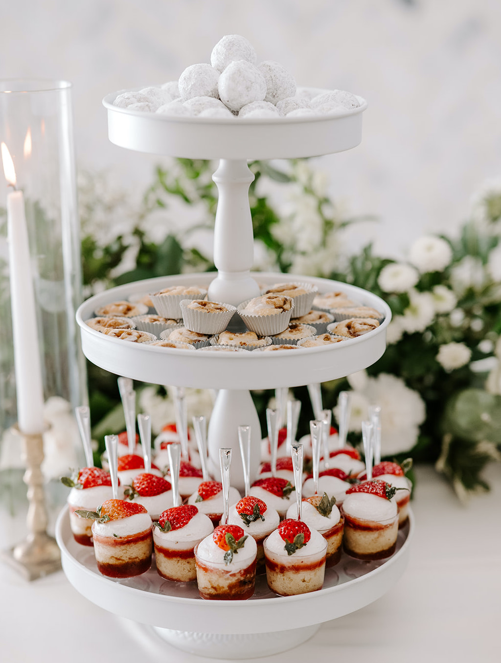 A dessert tray is full of yummy desserts with powdered sugar, strawberries and mini baked goods.