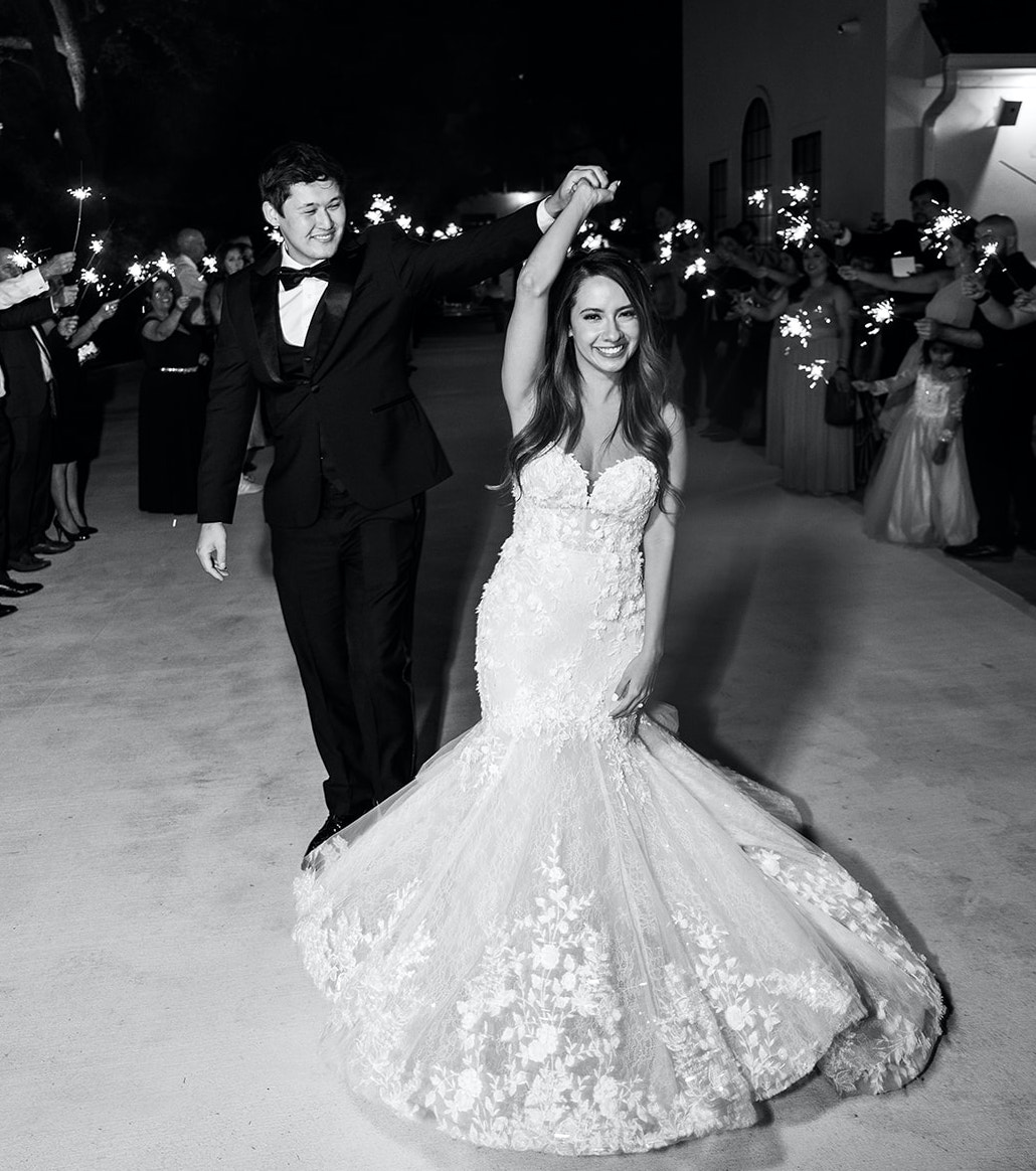 The bride and groom leave their whimsical wedding in a tunnel of sparklers held by their guests.