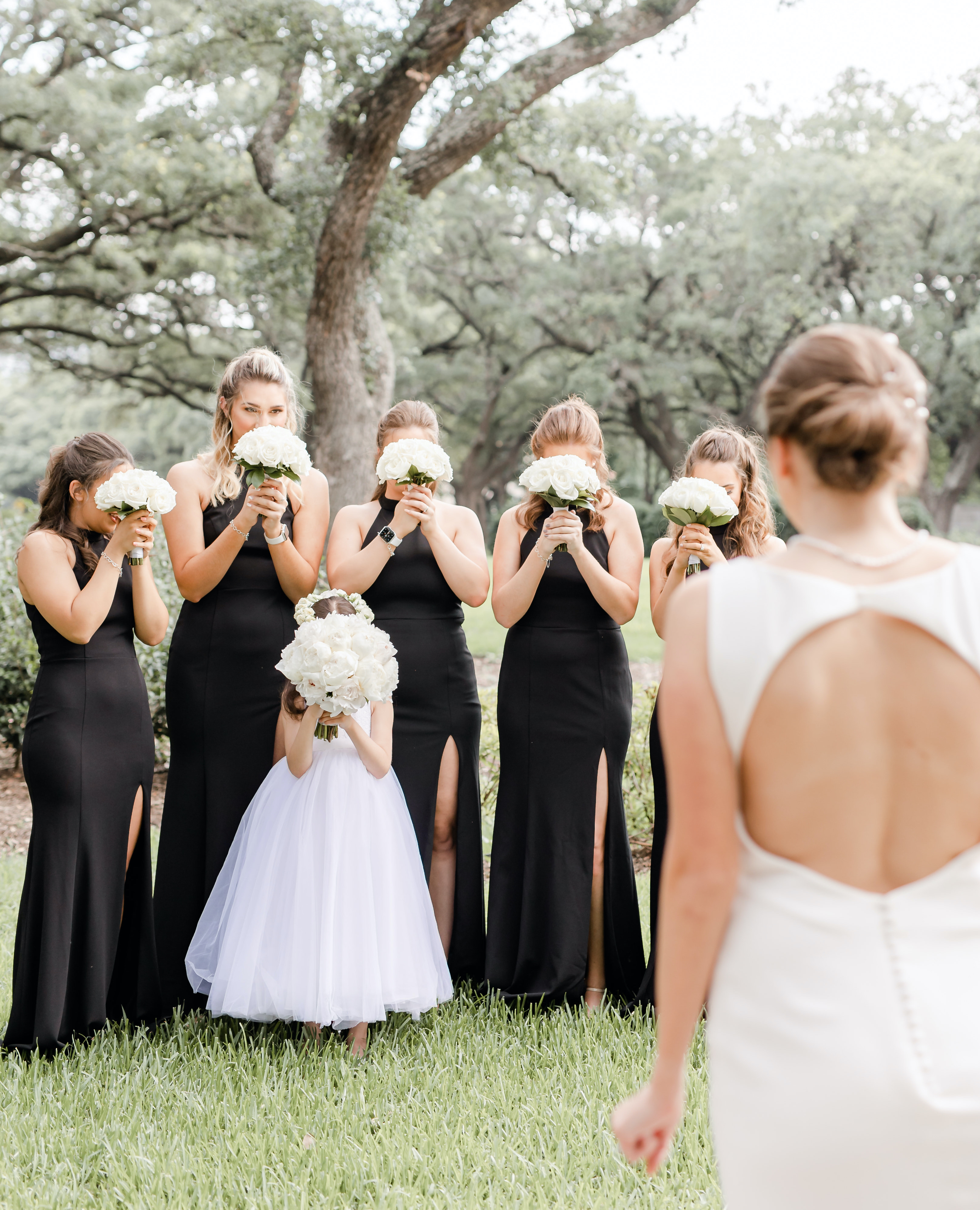 The bride waits for her bridesmaids to open their eyes to see her wedding gown. They are in the Houston museum district.