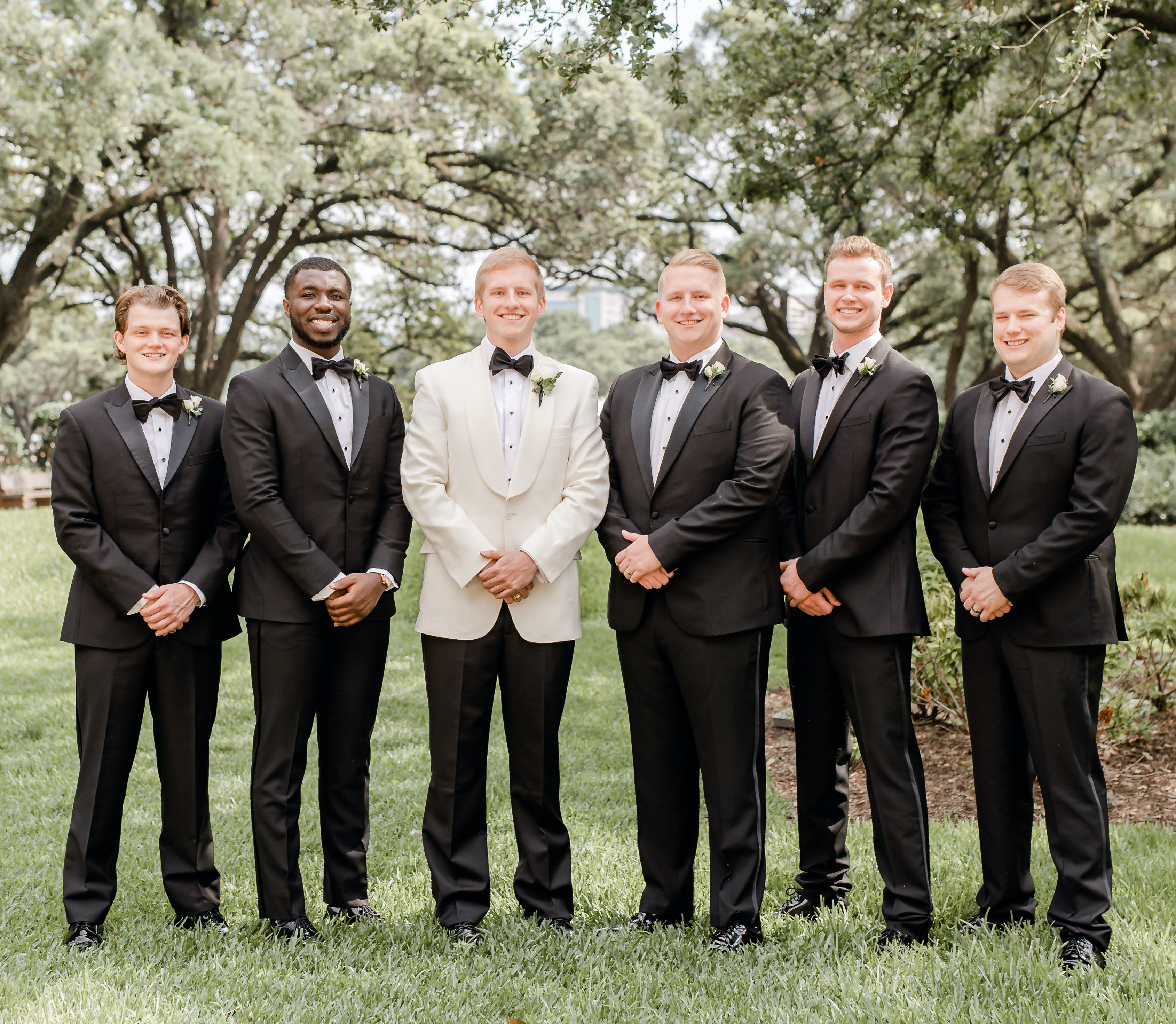 The groom stands with his groomsmen outside in Houston, TX for his ivory, black and champagne wedding.