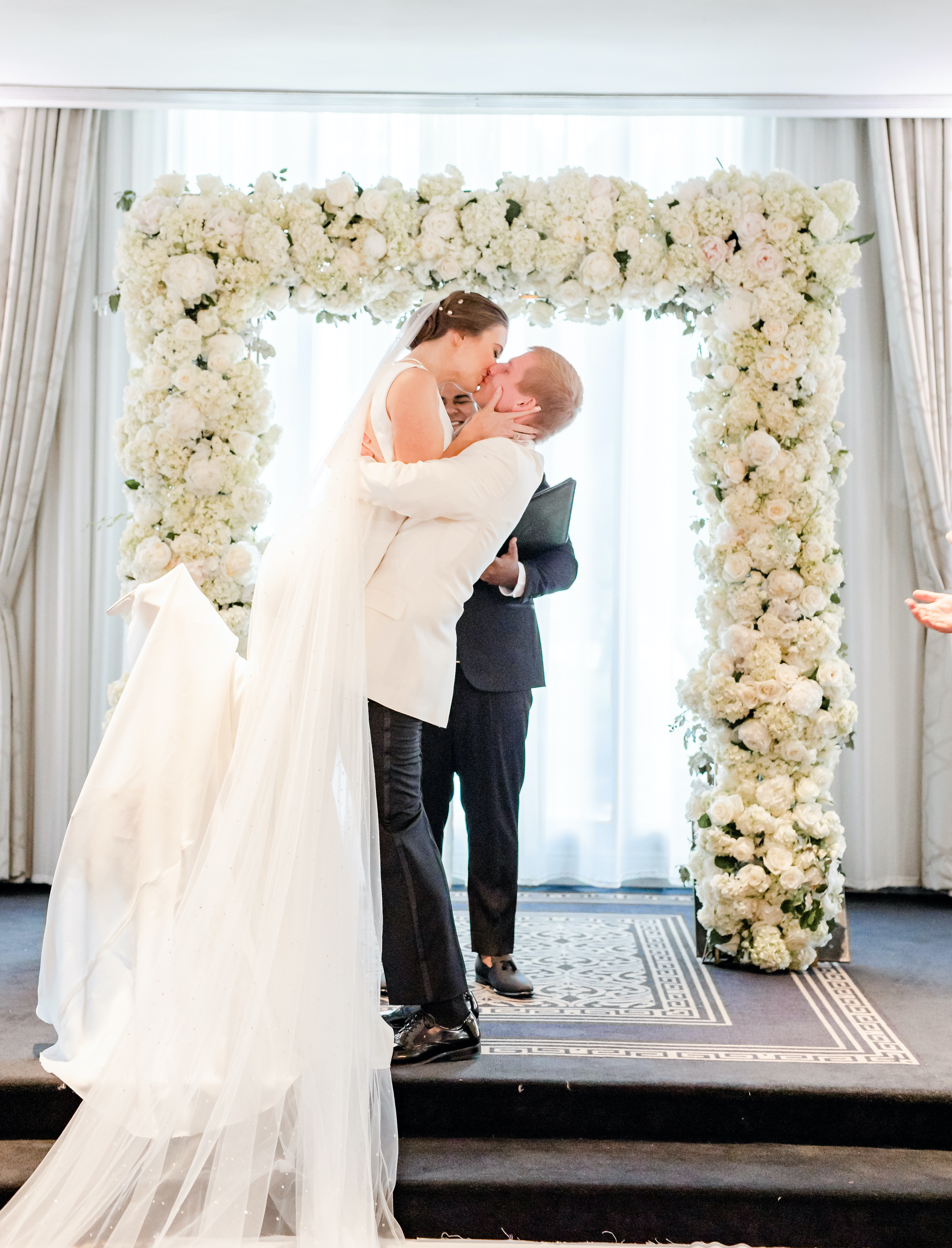 The groom lifts his bride in the air at the altar why they are kissing at their wedding ceremony in the Houston museum district.
