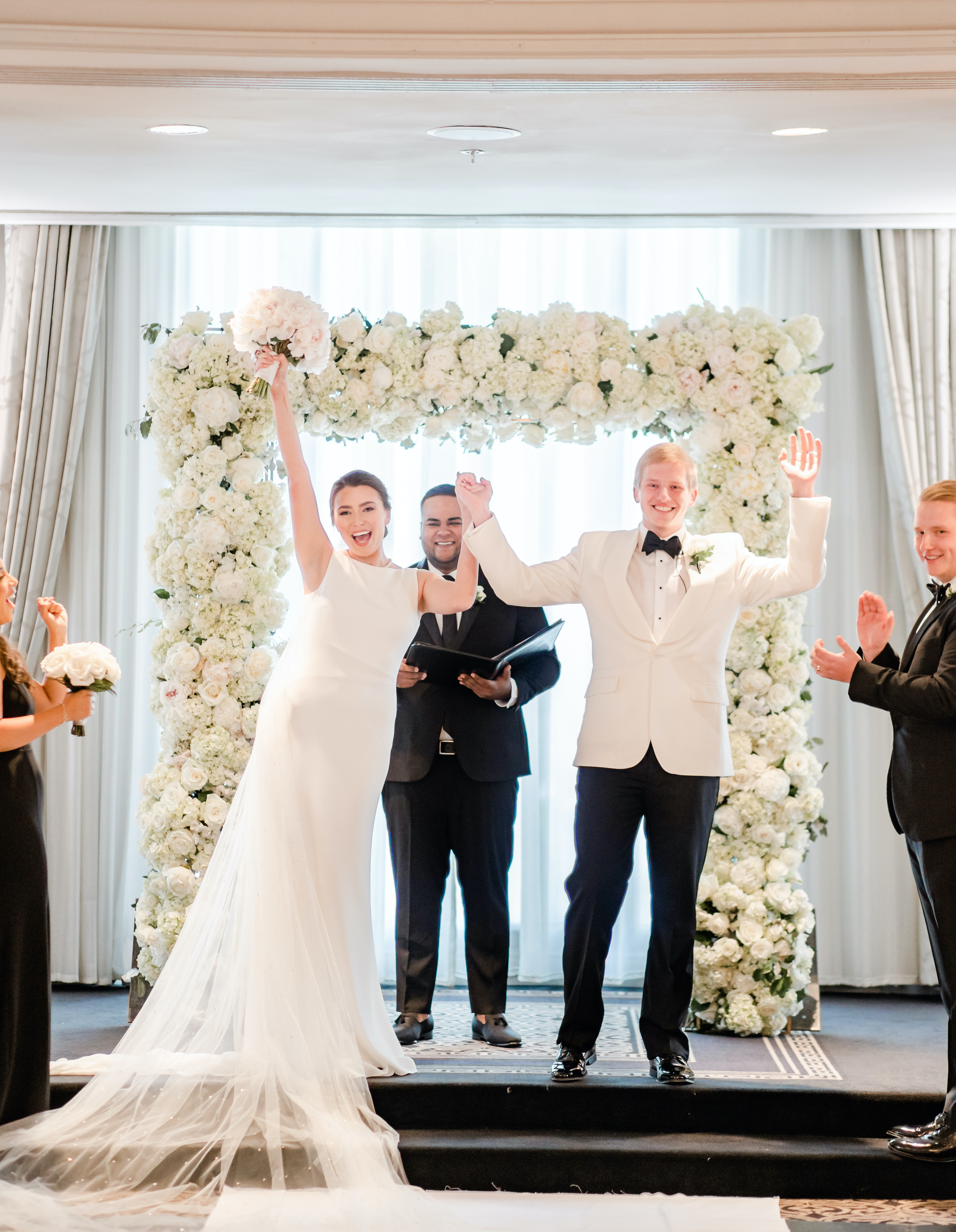 As the bride and groom are leaving the altar they raise their hands in front of their guests at their Houston wedding in the museum district.