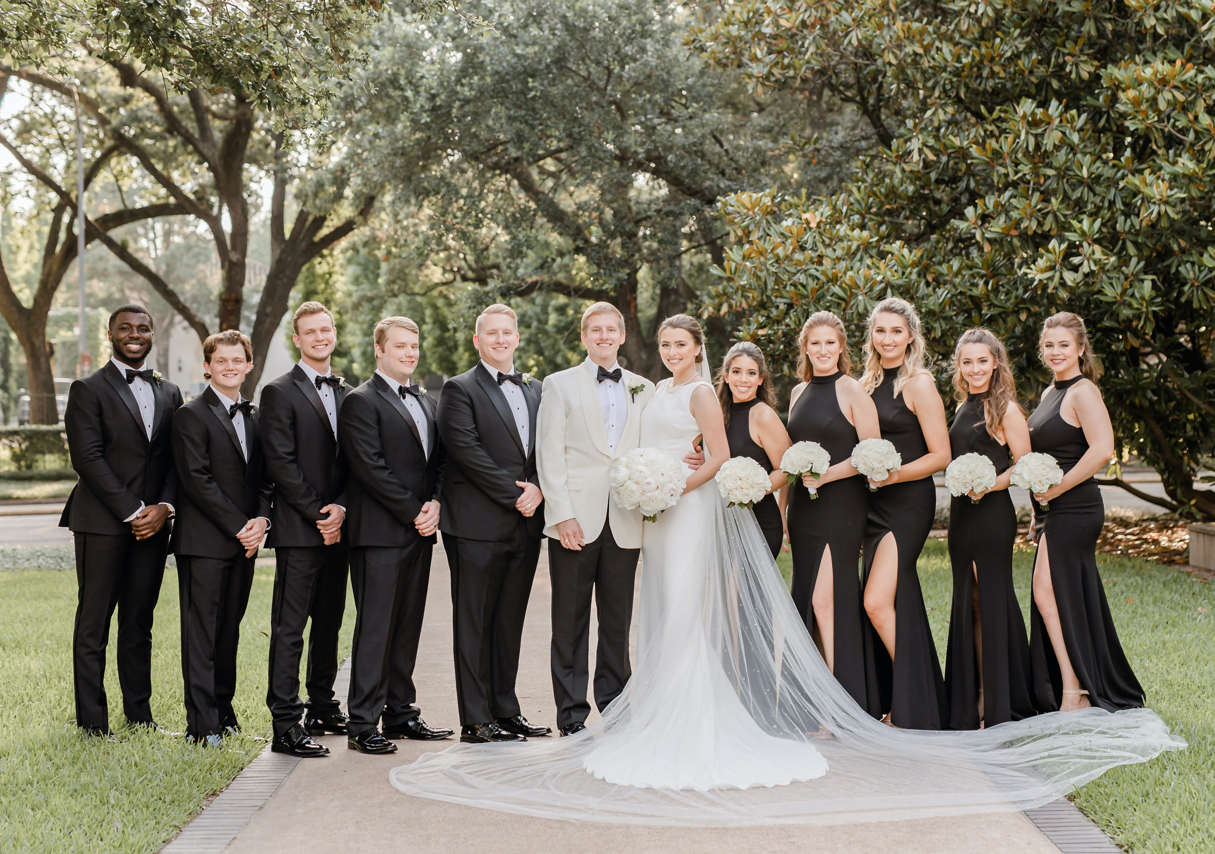 The newlyweds stand with their wedding party in the Houston museum district for their black, ivory and champagne wedding.