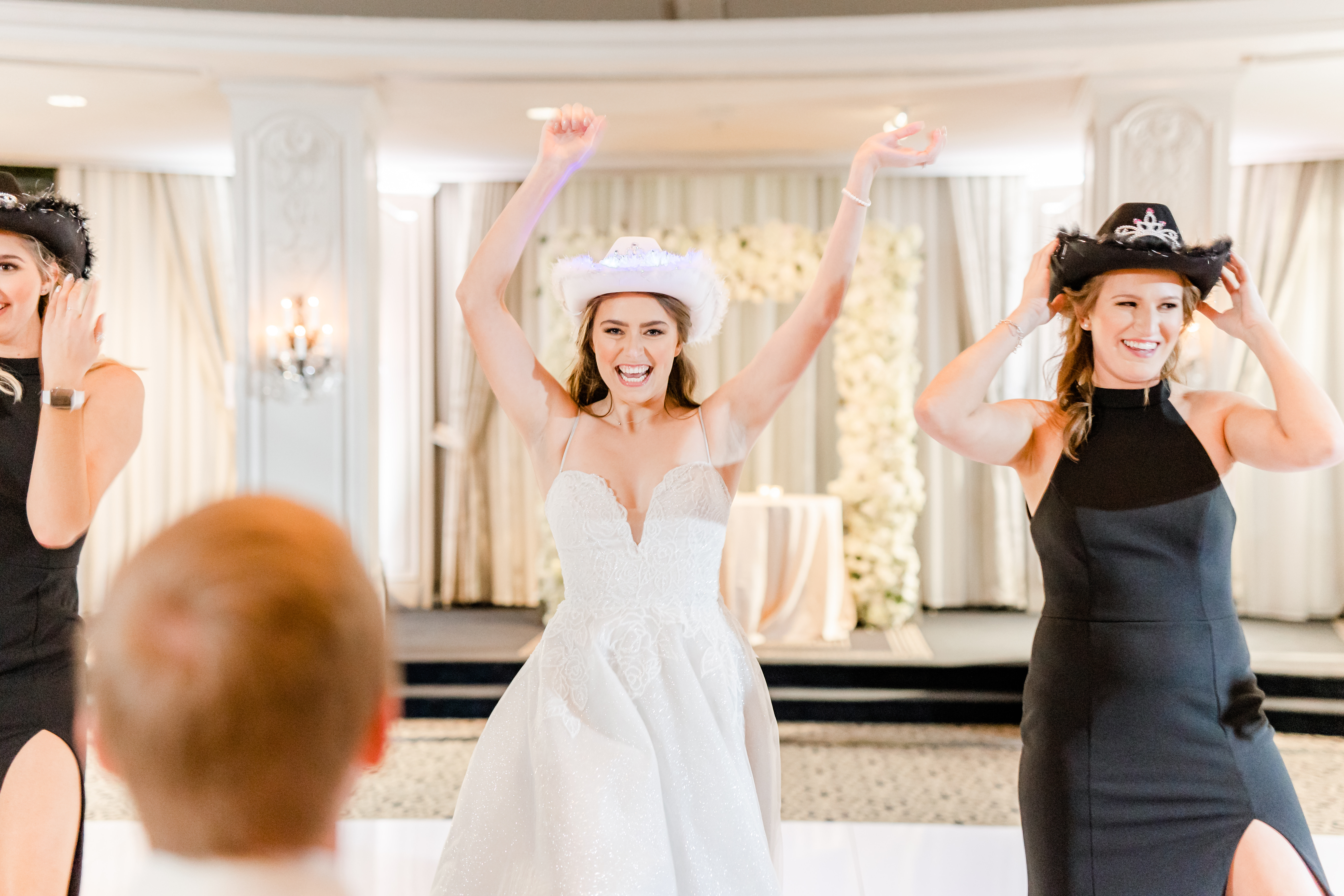 The bride smiles and has her hands in the air as she dances with her bridesmaids at her wedding reception in the Houston museum district.