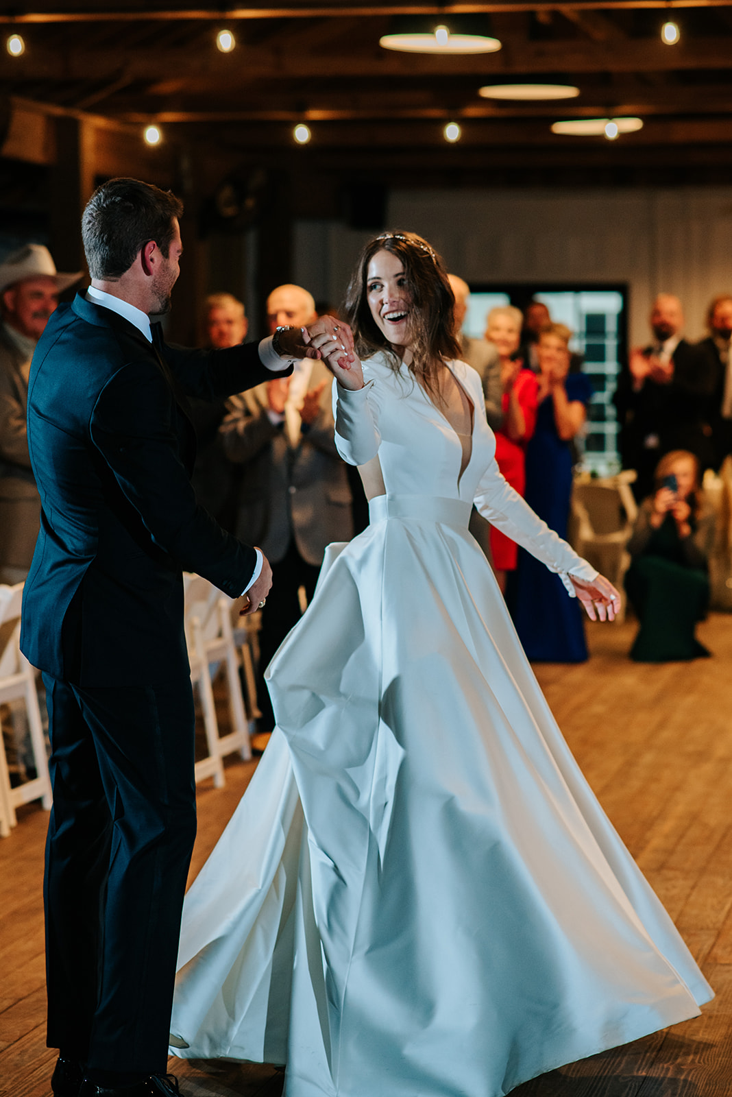 The groom twirls his bride on the dance floor at their winter wedding reception at 7F Lodge in College Station, TX.