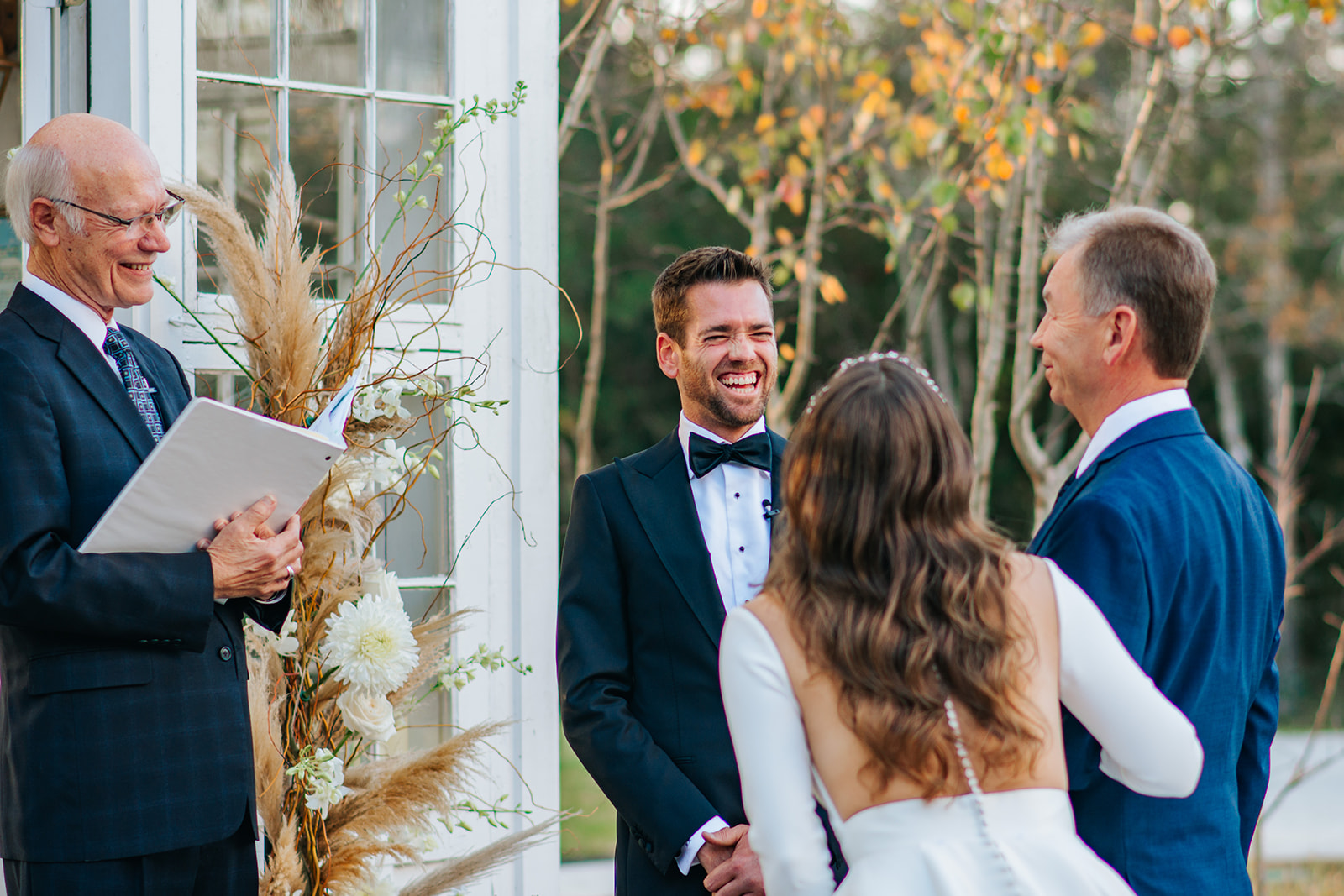 The groom laughs with his bride and her father at the altar before they say "I Do" at their winter wedding at 7F Lodge in College Station, TX.