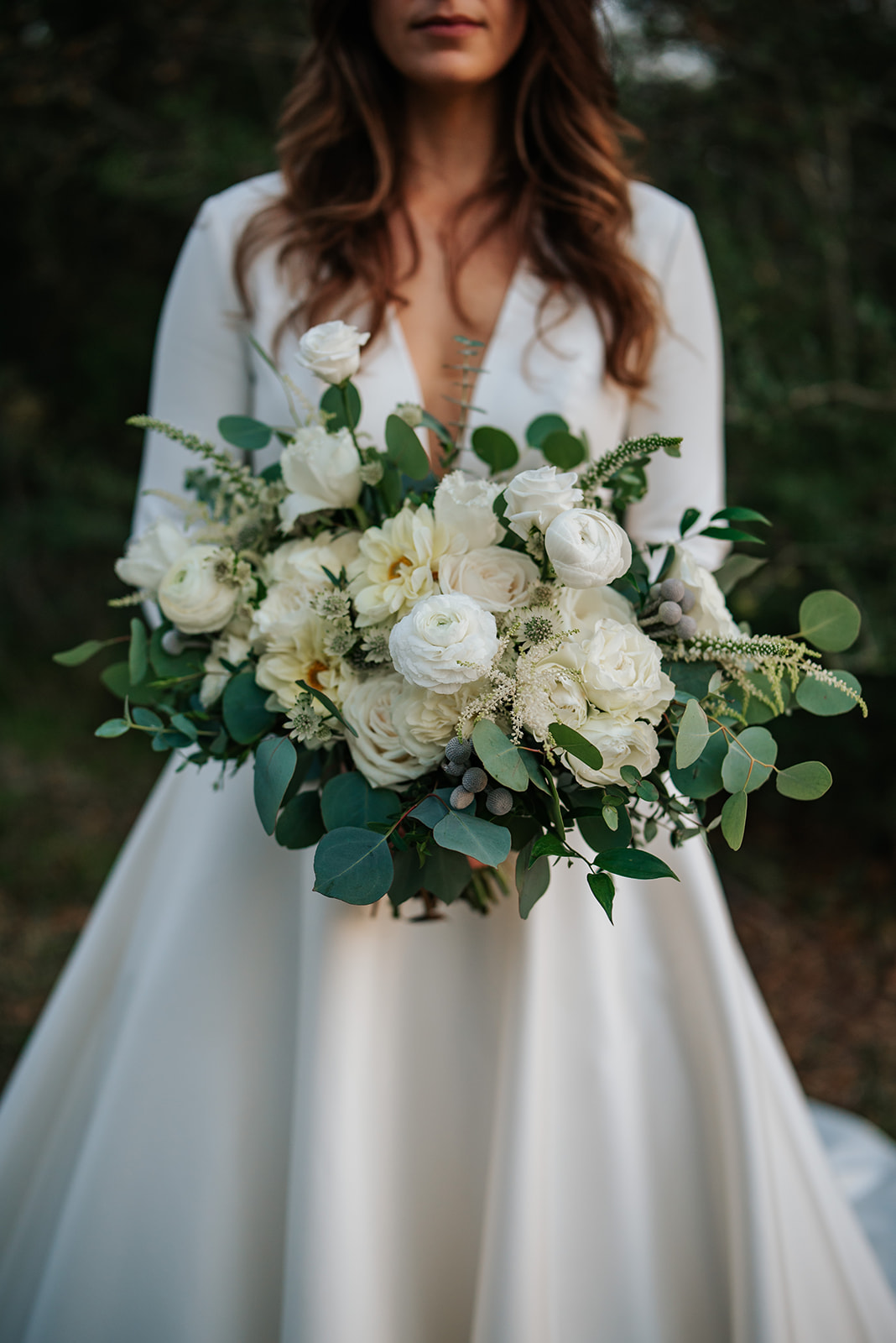 A close up photo of the bride's flower bouquet full of white and ivory flowers including Ranunculus, garden roses and Dahlias. 