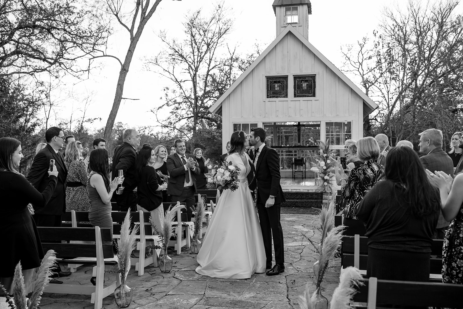 The bride and groom kiss while walking down the aisle of their intimate alfresco winter wedding at 7F Lodge in Aggieland.