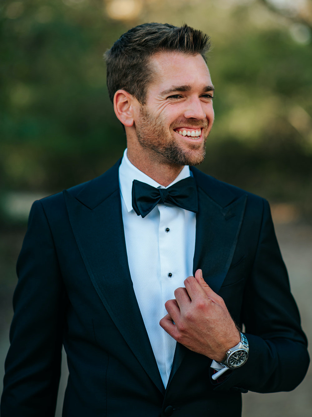 The groom smiles in his suit and bowtie at his winter wedding at 7F Lodge in College Station, TX.