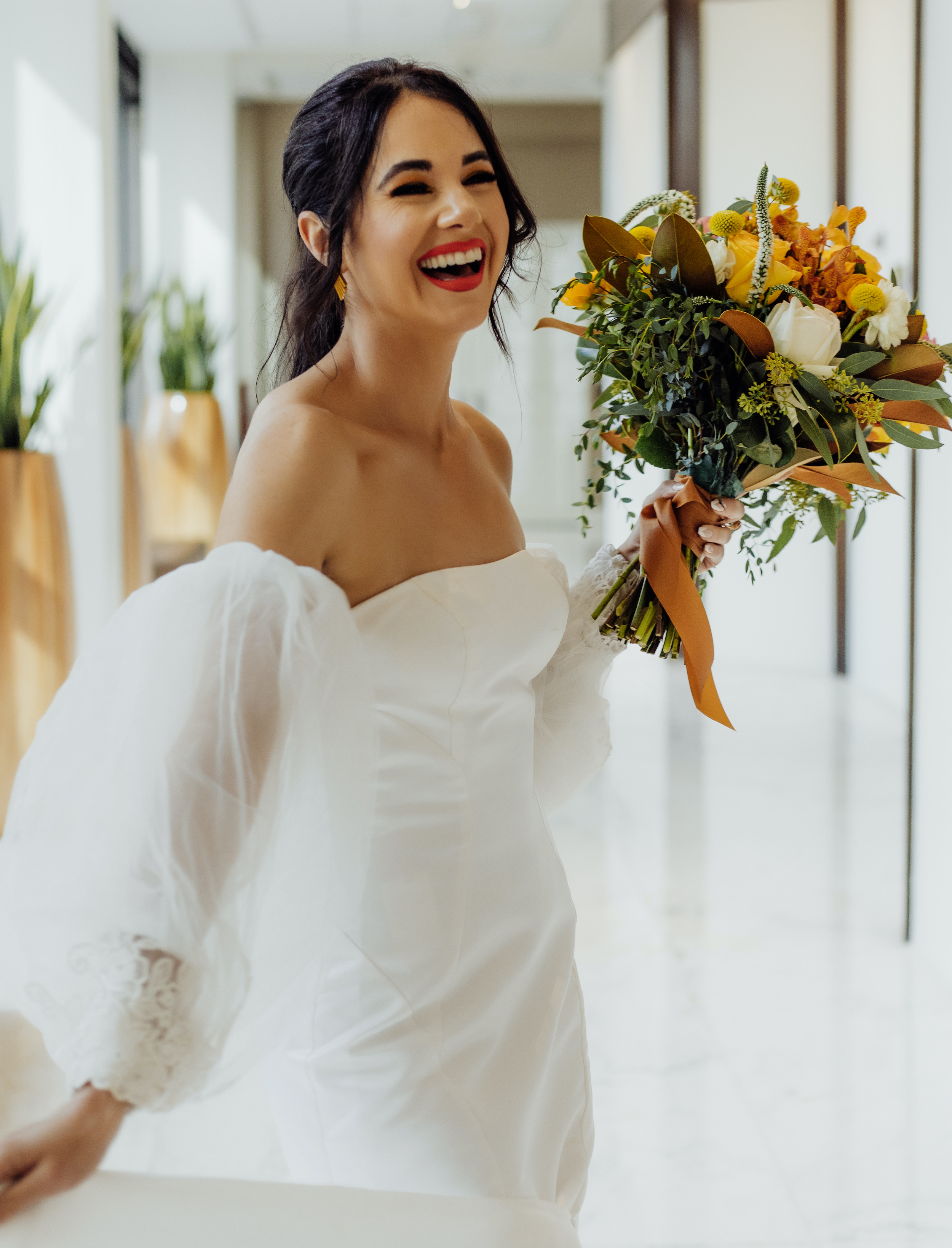 The bride laughs and holds her bouquet near her face at The Whitehall in Houston, TX.