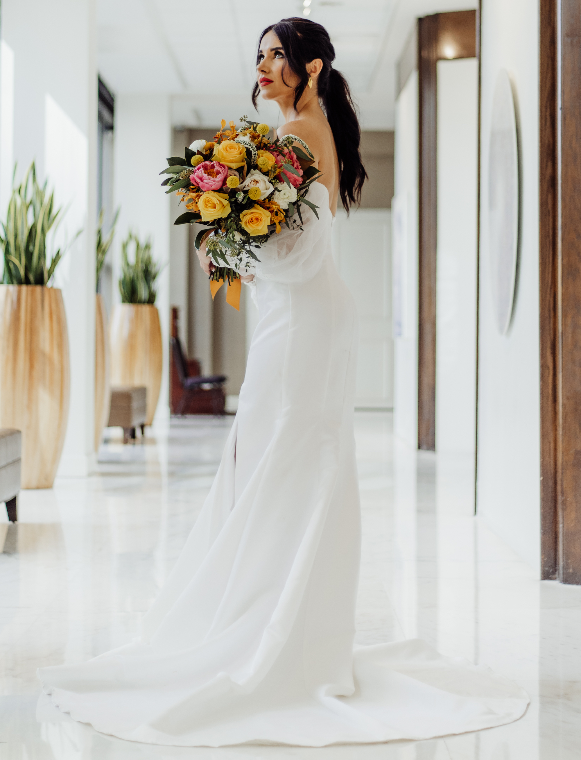 The bride holds her bouquet and looks up, posing for a vibrant retro-inspired styled shoot photo.