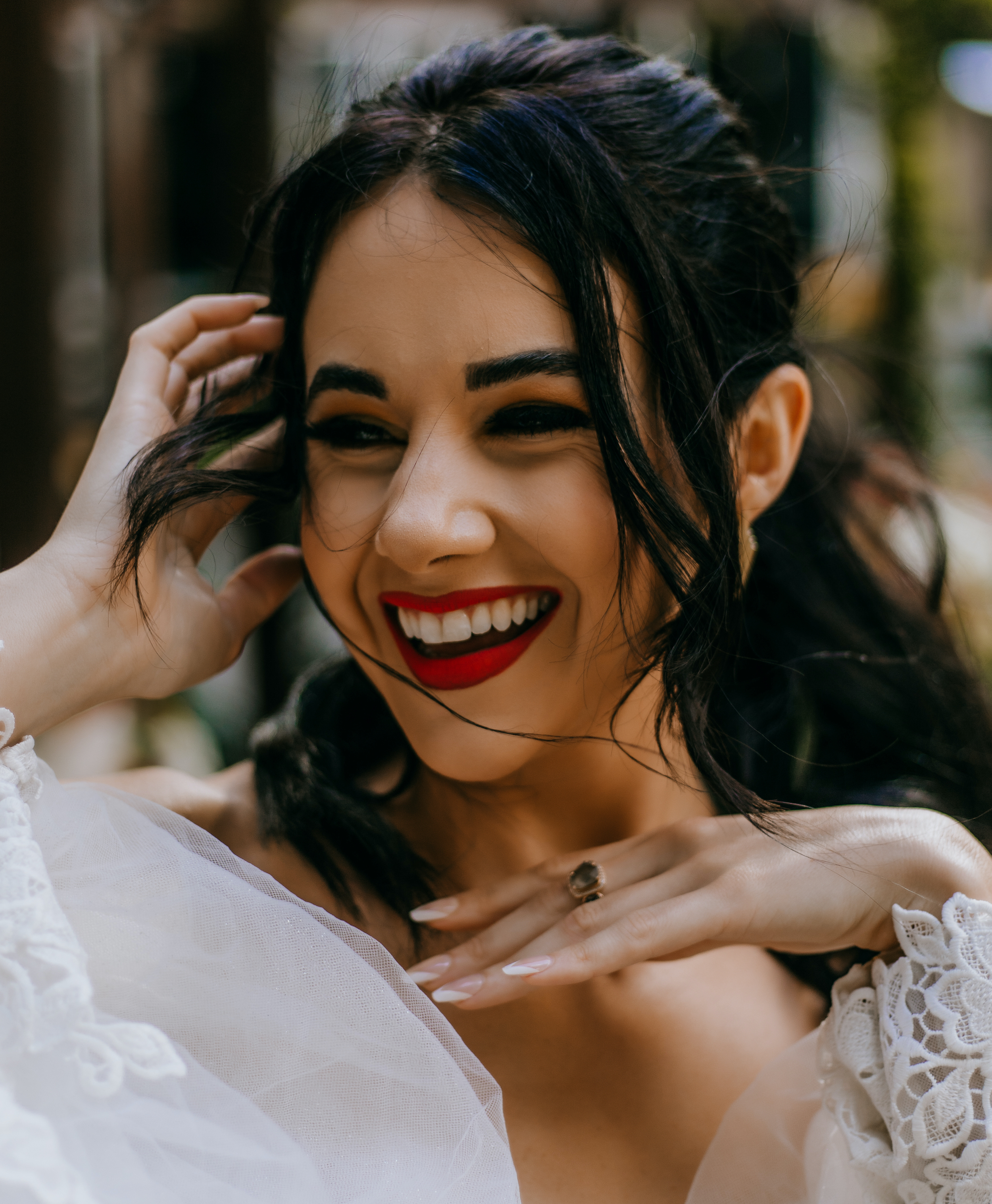 Women with ponytail and red lipstick smiles while pushing her hair back with one hand at a wedding styled shoot at The White Hall, a wedding venue in downtown Houston.