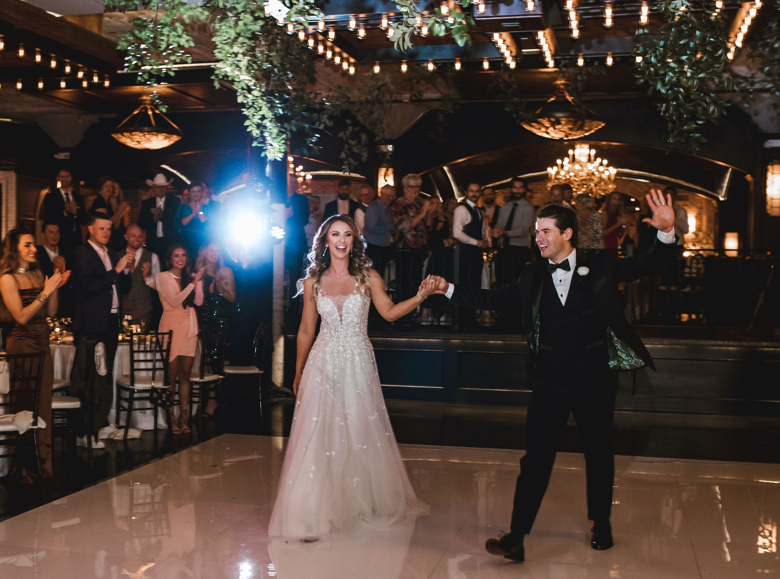 The bride and groom wave to their wedding guests as they head to the middle of the dance floor at their wedding reception at The Astorian in Houston, TX. They have their first dance and celebrate their love story at The Astorian.