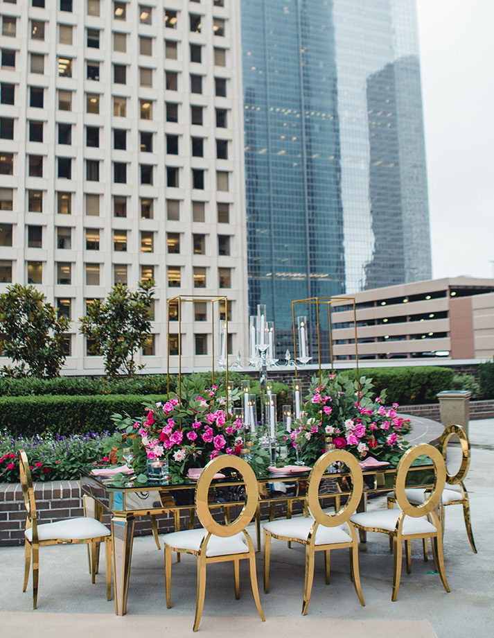 A rooftop wedding set up with vibrant pink flowers and gold accents at the Hyatt Regency Downtown in Houston, TX.