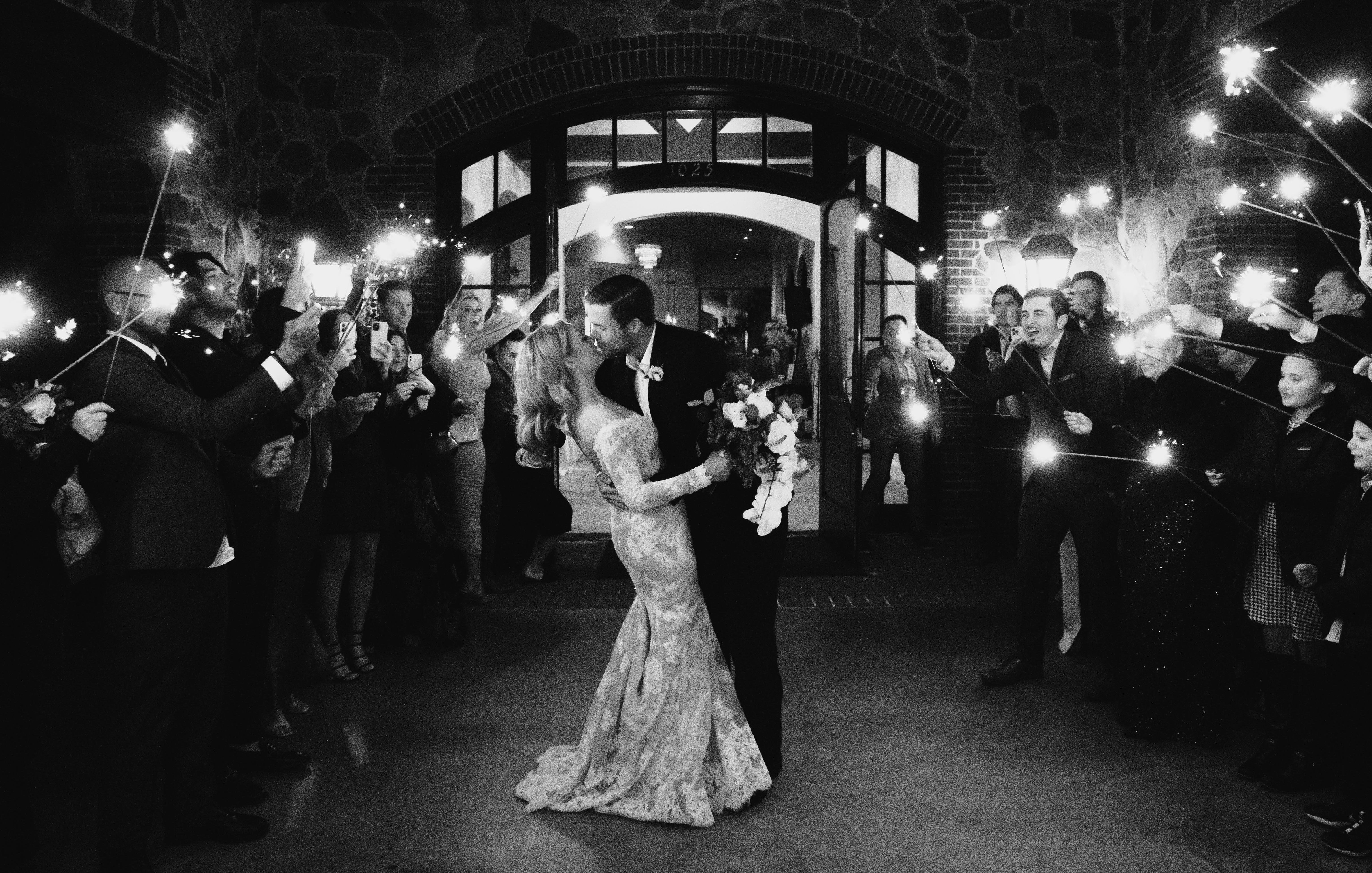 A black and white photo of the bride and groom leaving their wedding in Houston, surrounded by their guests holding sparklers.