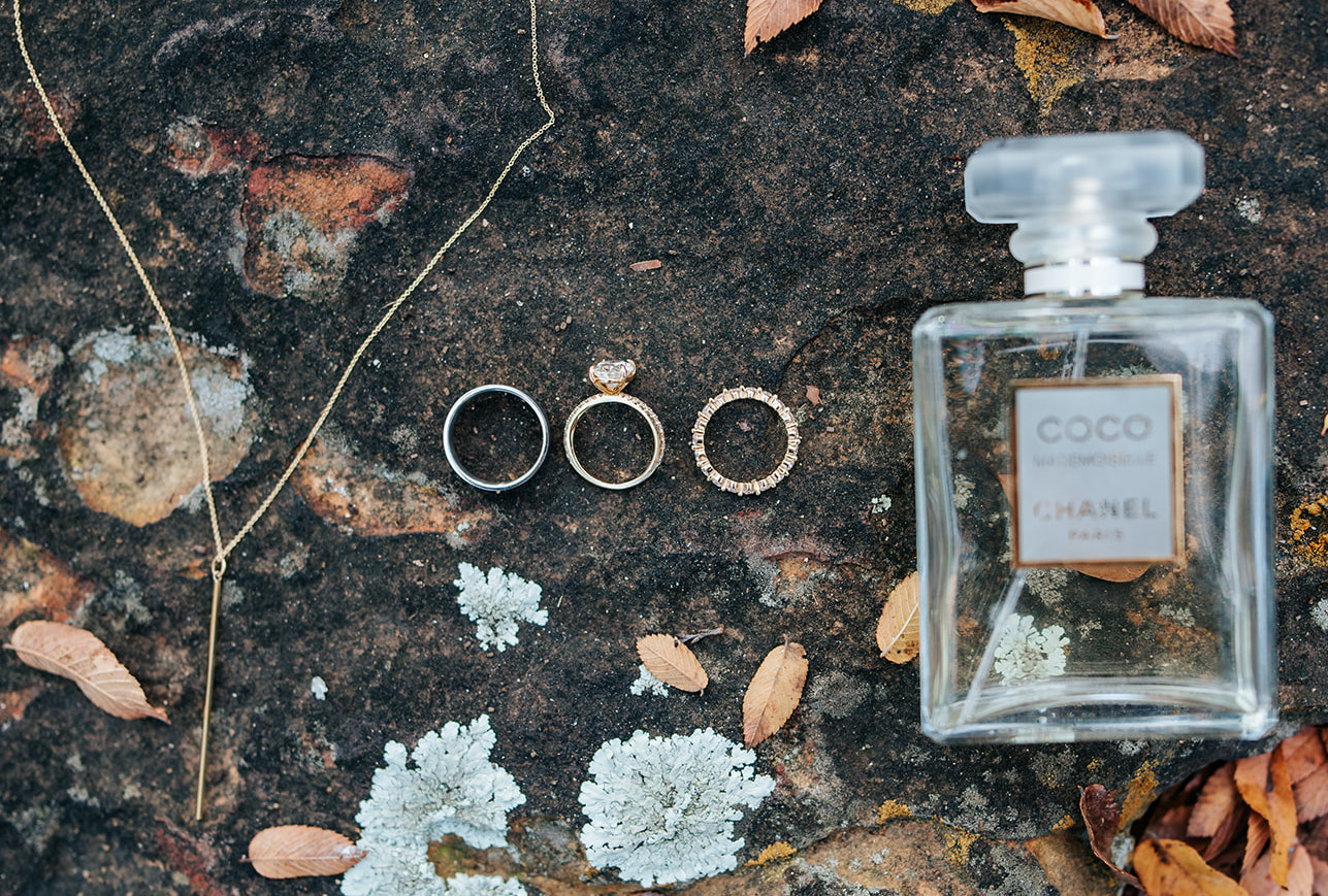 The bride and groom's wedding rings are placed on the ground next to fall leaves at 7F Lodge in College Station, TX.