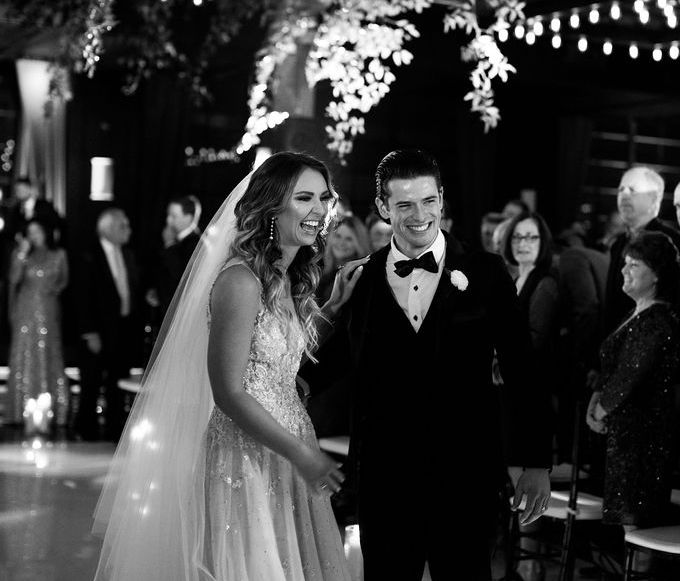 The bride and groom have big smiles on their faces as they walk down the aisle of their wedding and celebrate their love story at The Astorian in Houston, Texas.