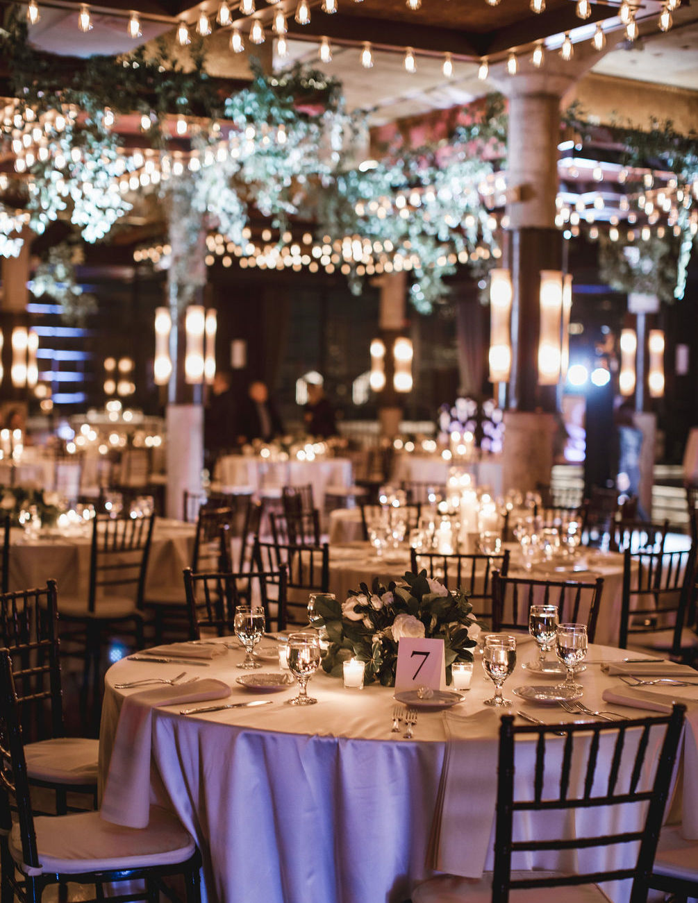 A table is set up at a wedding reception with white flowers and greenery at The Astorian in Houston, Texas.