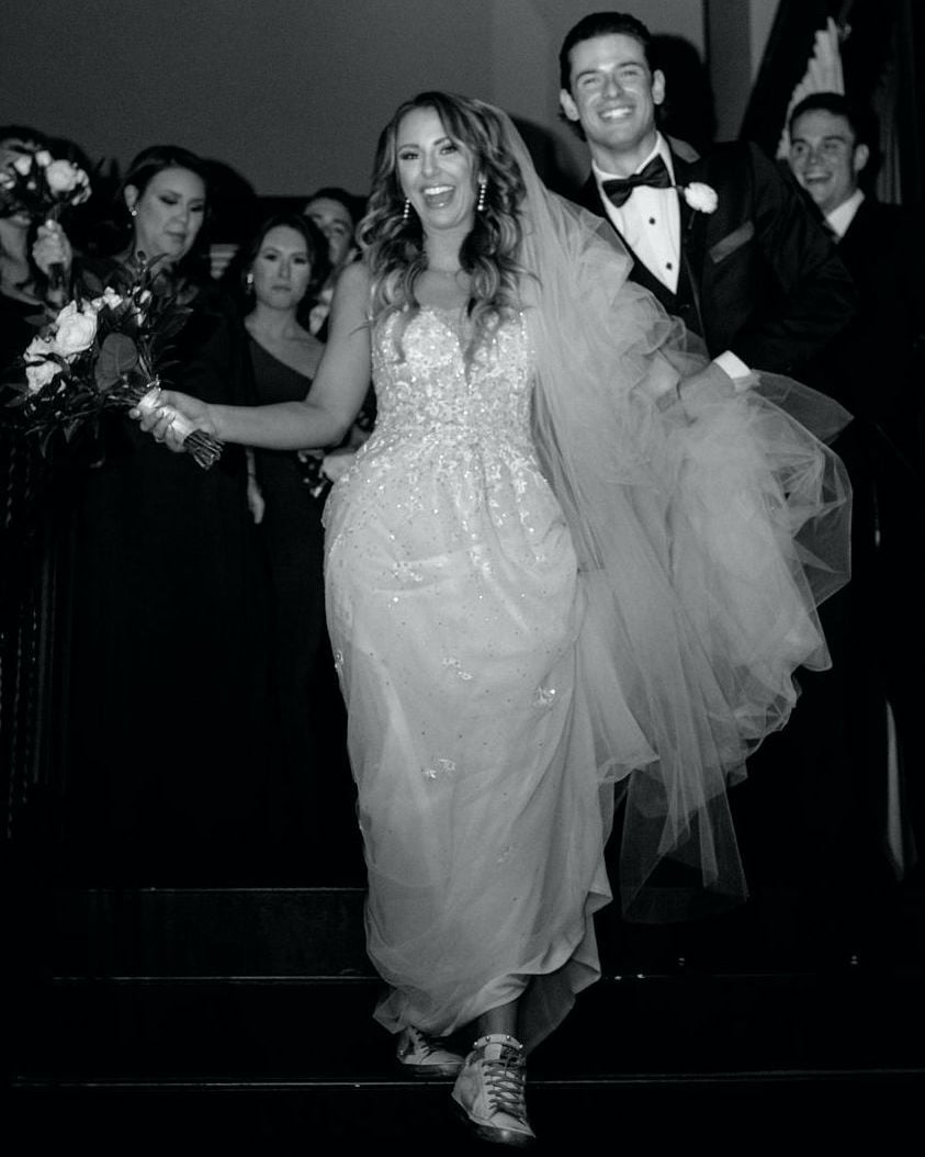 The bride walks down the stairs with her groom behind her at the end of the celebration of their love story at The Astorian in Houston, TX.