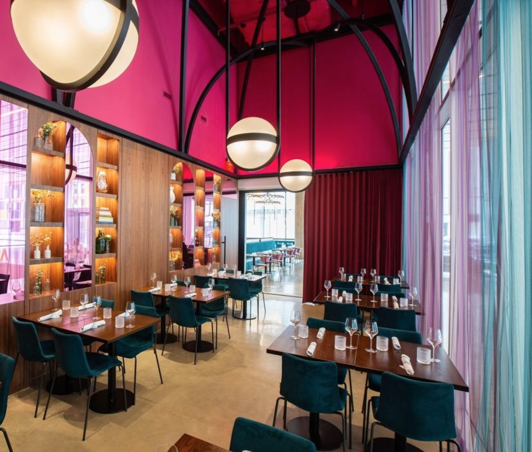 A photo of one of the rooms in Common Bond Brasserie in the Theater District in Houston, TX. The architecture is very modern with pops of bright pink, purple and blue.