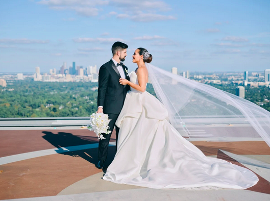 A bride and groom are standing on top of a helicopter pad at The Post Oak Hotel at Uptown Houston.