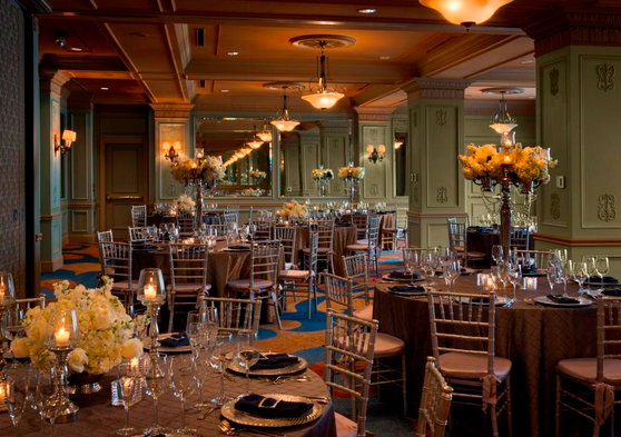 A ballroom in Hotel Icon in Houston, TX is set up for a wedding with ivory flowers and candles.