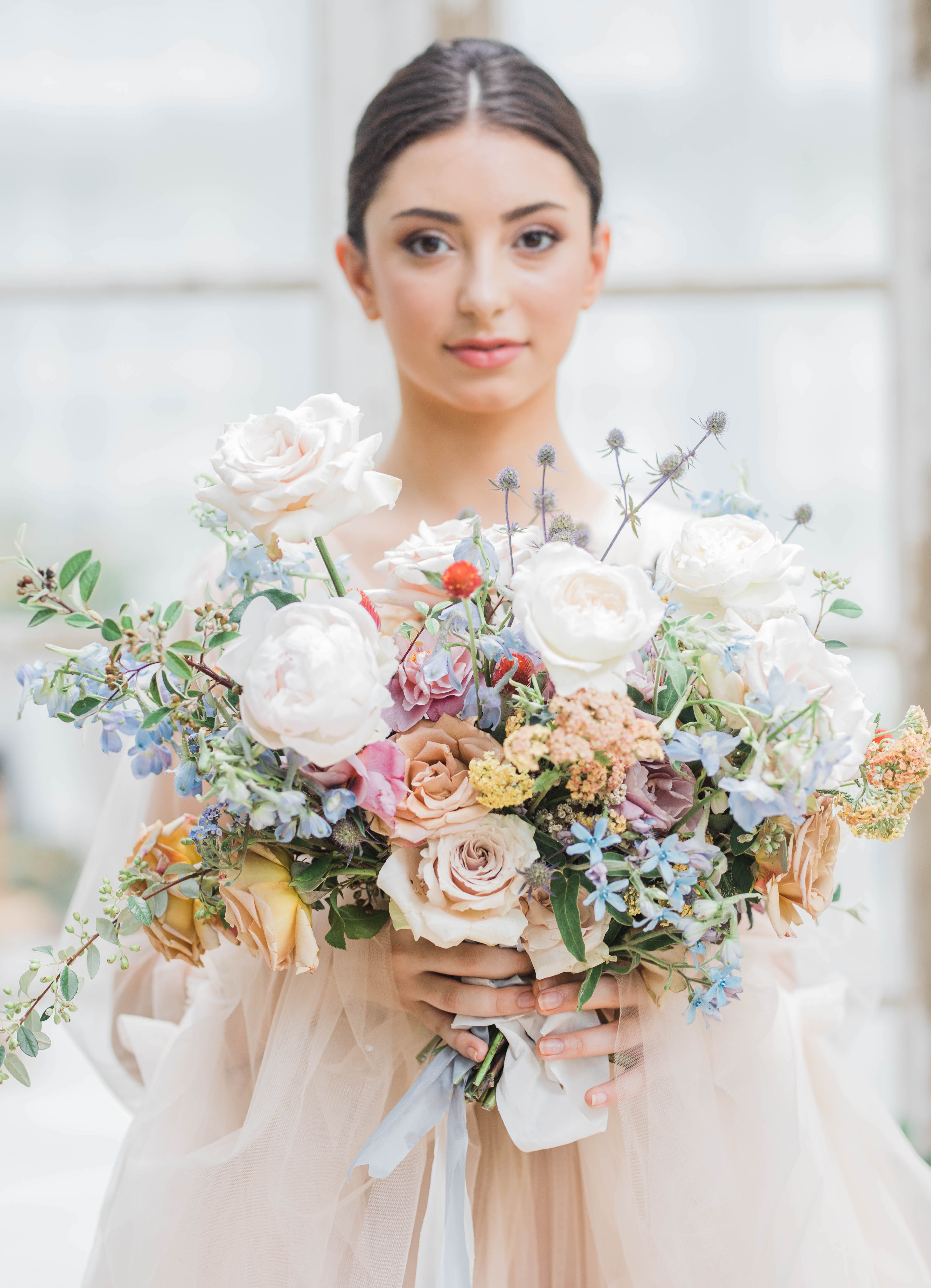 A bride holds a colorful bridal bouquet.