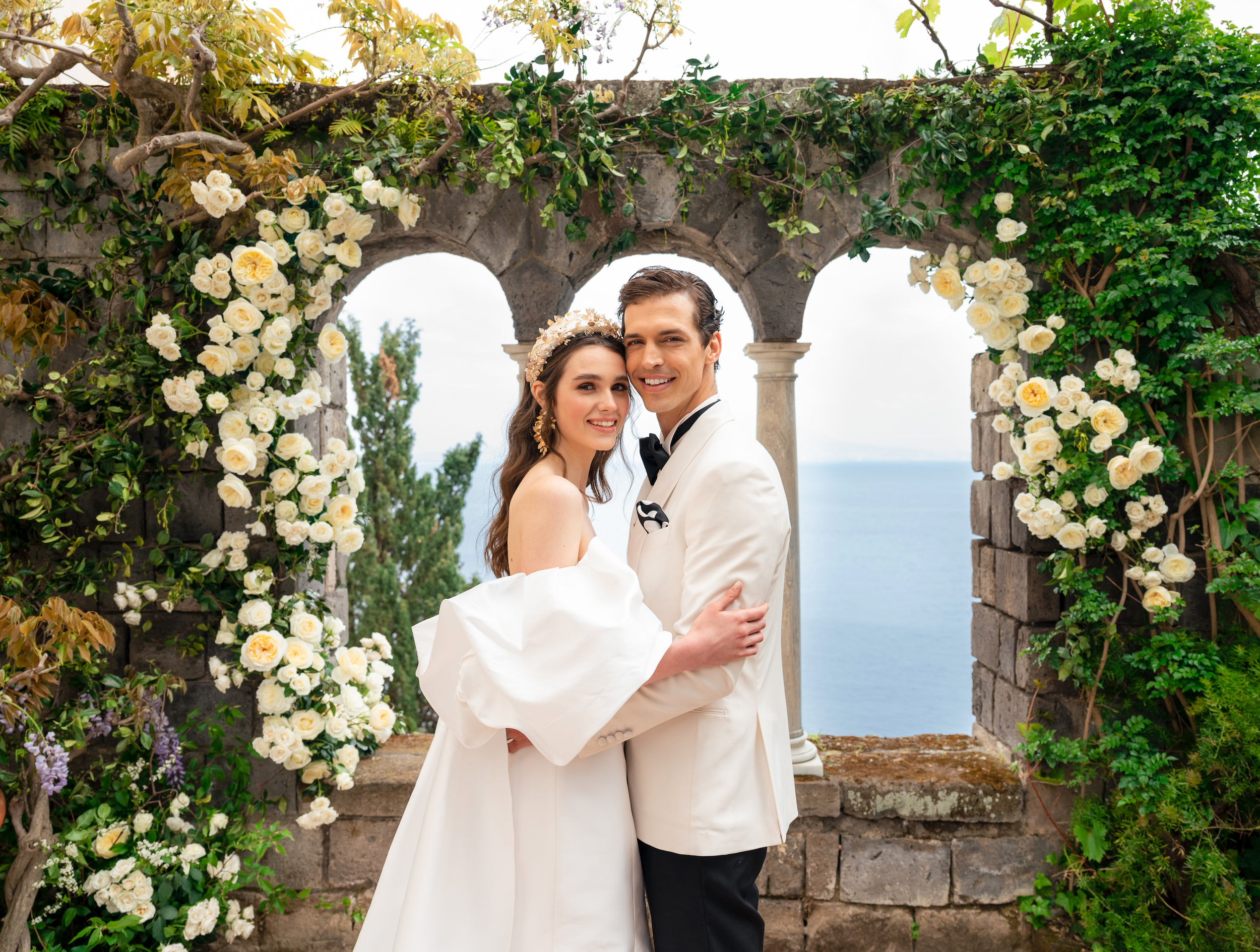 A bride and groom hold each other and smile at the altar that has an ocean view in Italy.