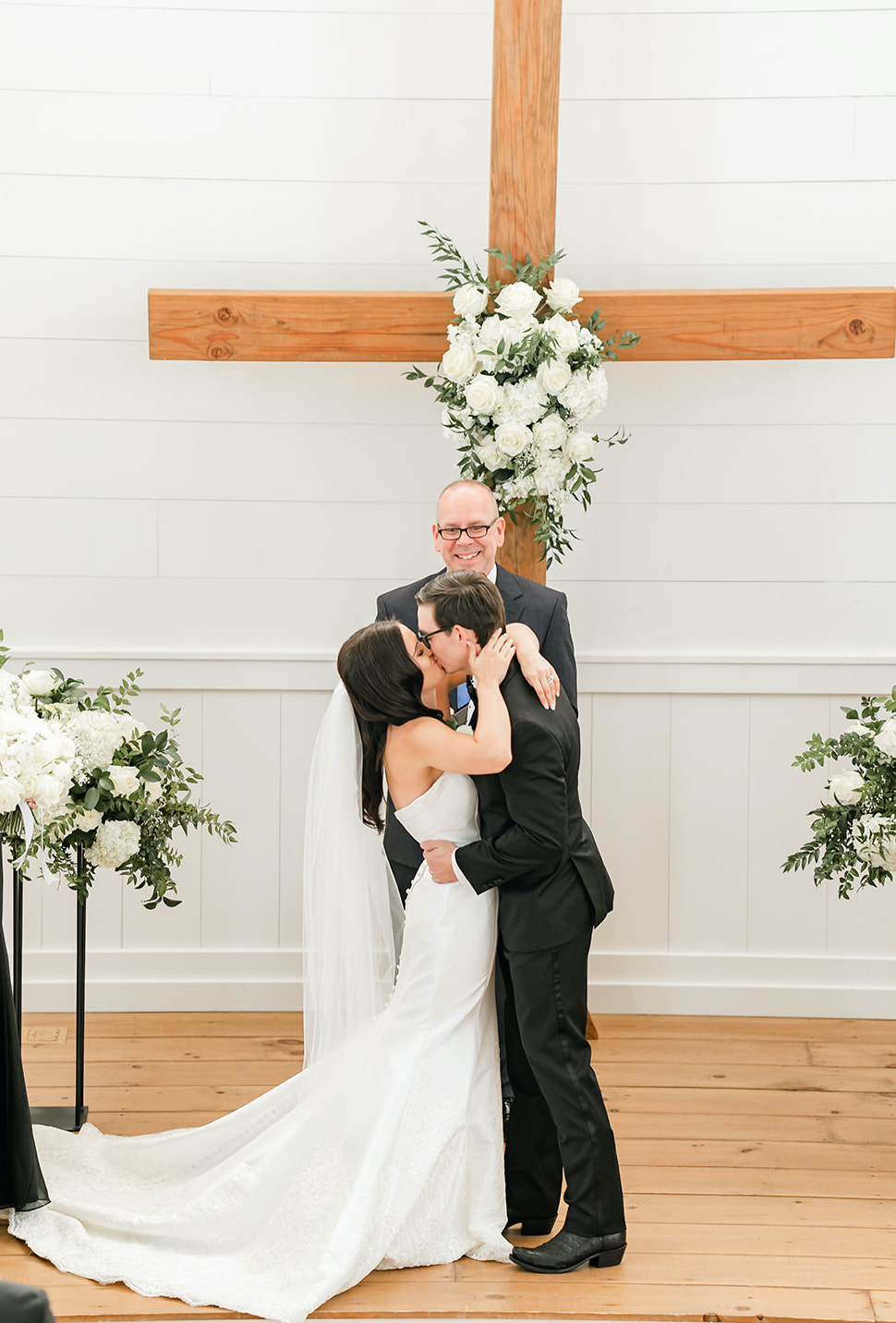 A bride and groom kiss at the altar of their elegant summer wedding in Montgomery, TX.