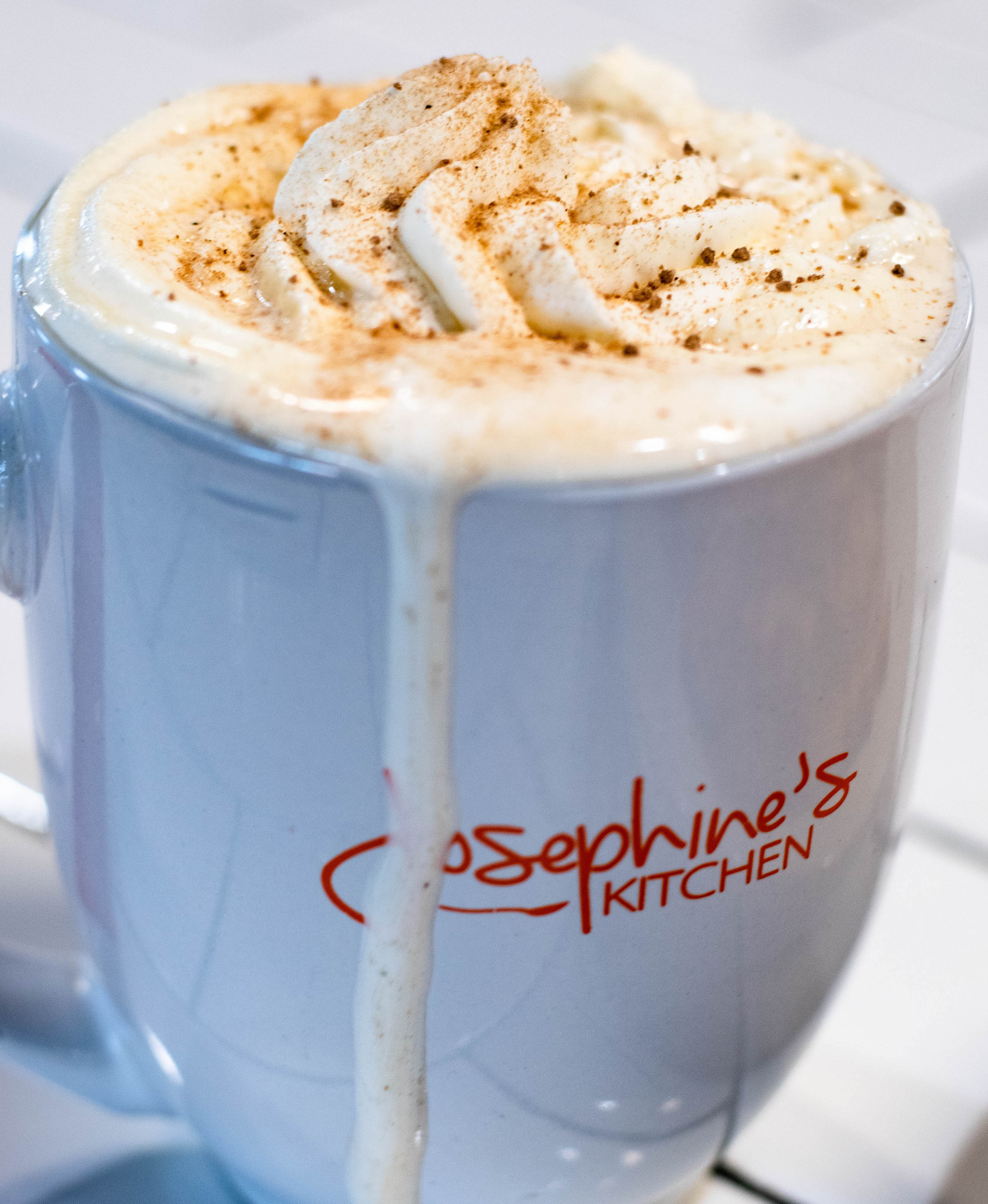 A white coffee mug topped with whipped cream sits on a counter at Josephine's Kitchen in South Padre Island, TX.