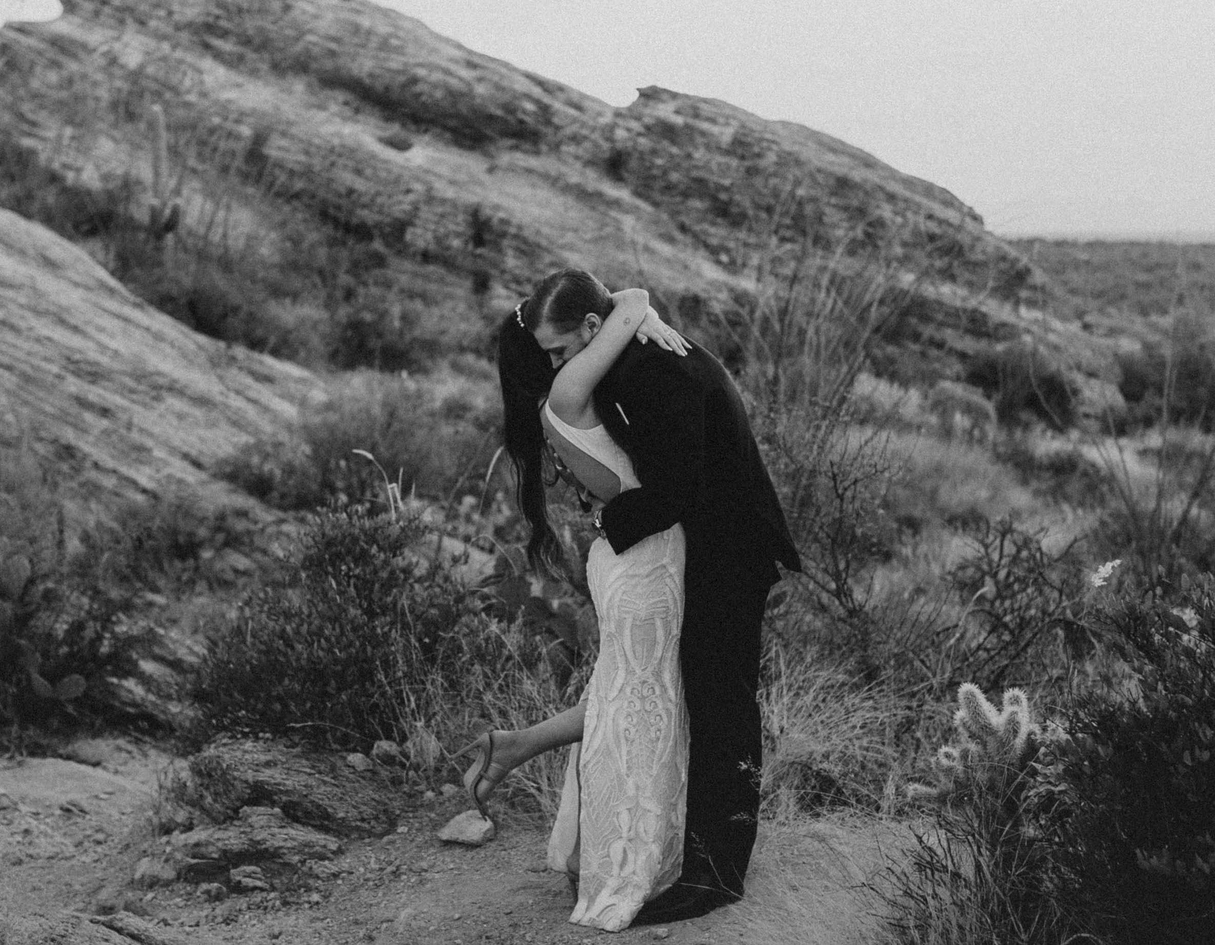 The bride and groom hug in the desert where their elopement is taking place.
