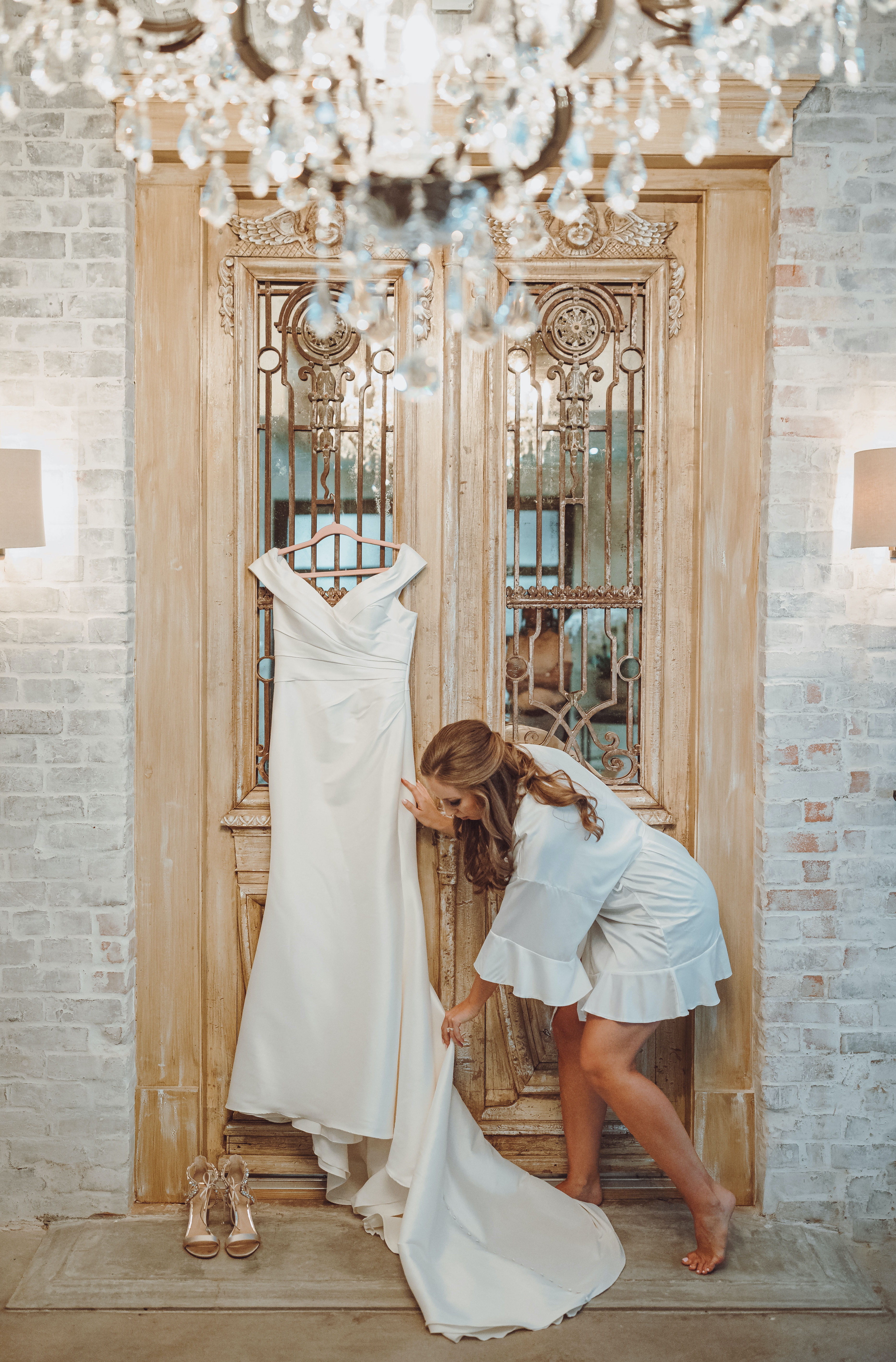 A bride fixes her dress that is hanging for her to put on in the bridal suite of The Astorian.