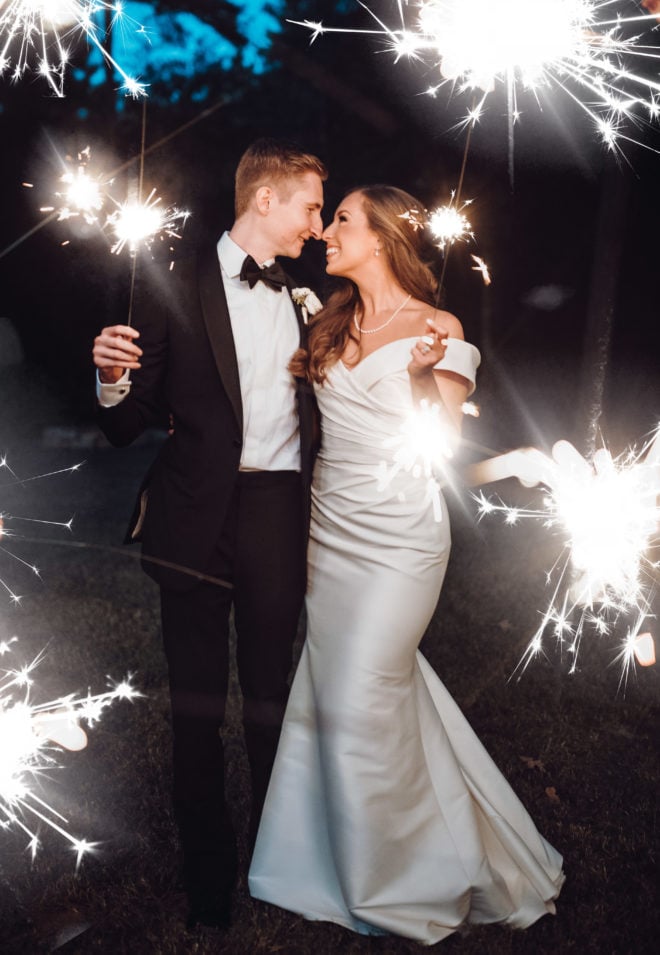 Bride and groom look at each other while holding sparklers at the end of their ceremony at a private home in Houston.