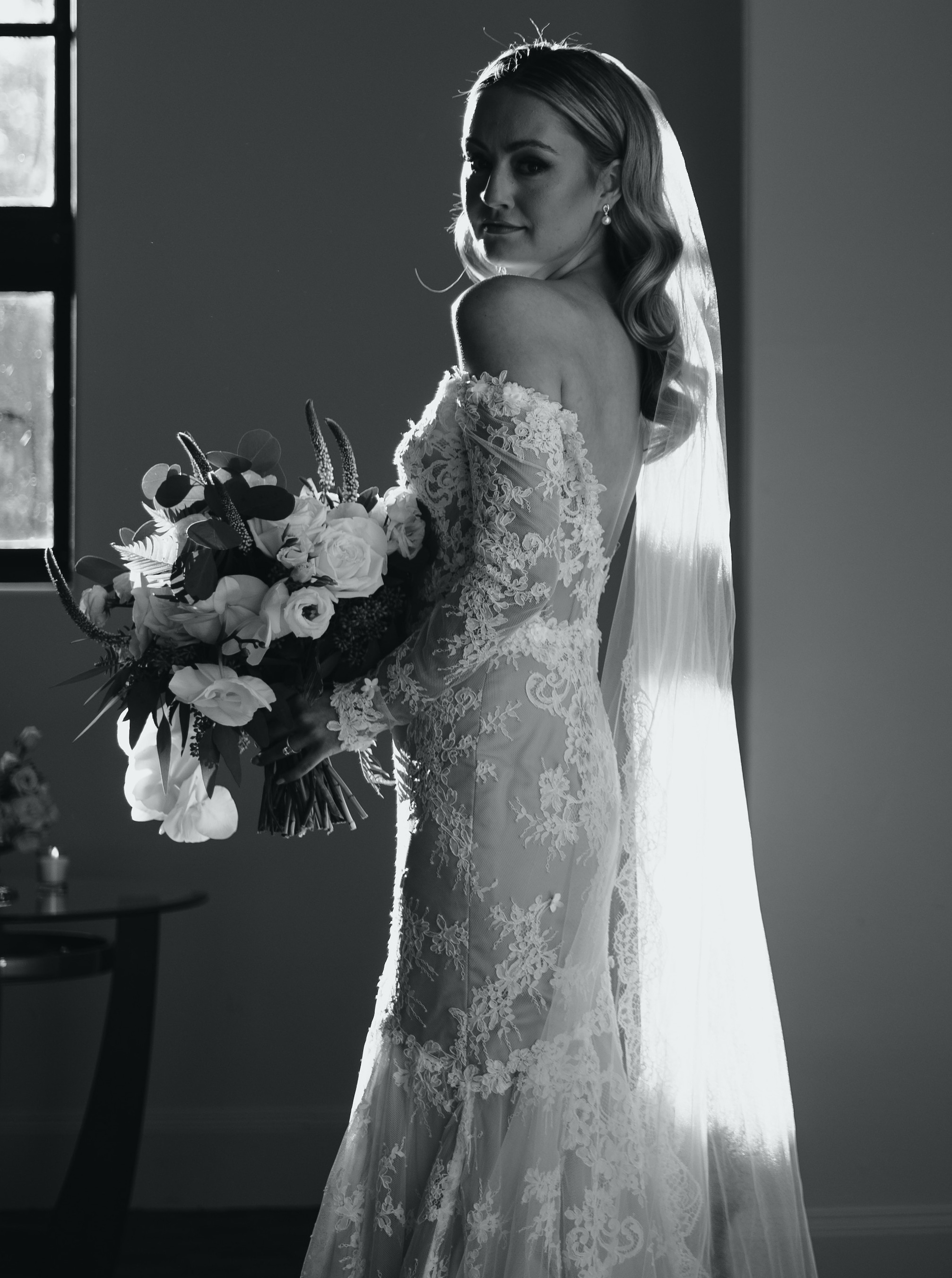 Christina Creedon looks at the camera in her wedding dress, holding her white and green bridal bouquet before her Houston wedding.