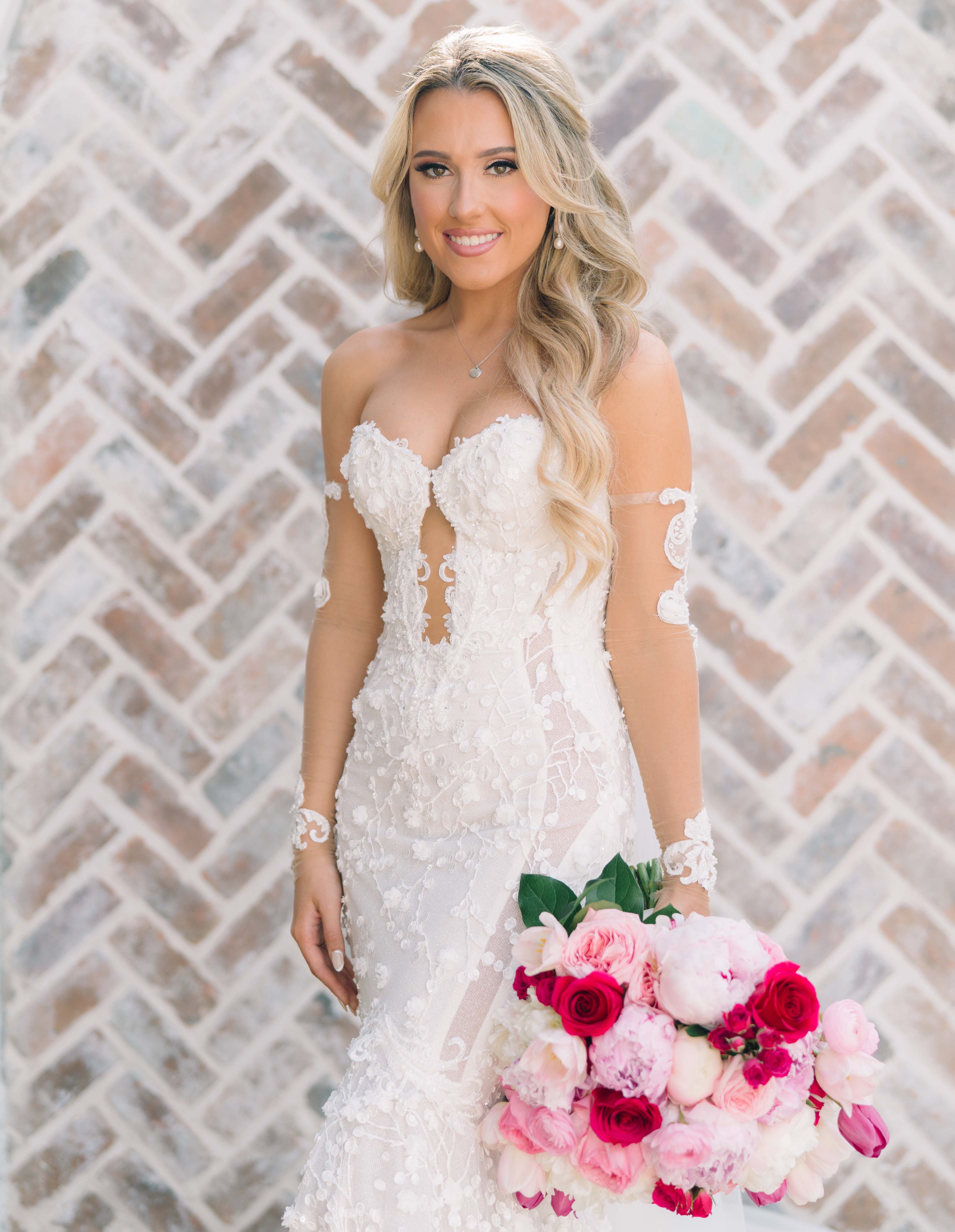 A bride smiles in a Galia Lahav gown and is holding a bright pink bridal bouquet for her Summer Wedding With a Vibrant Palette of Pink.