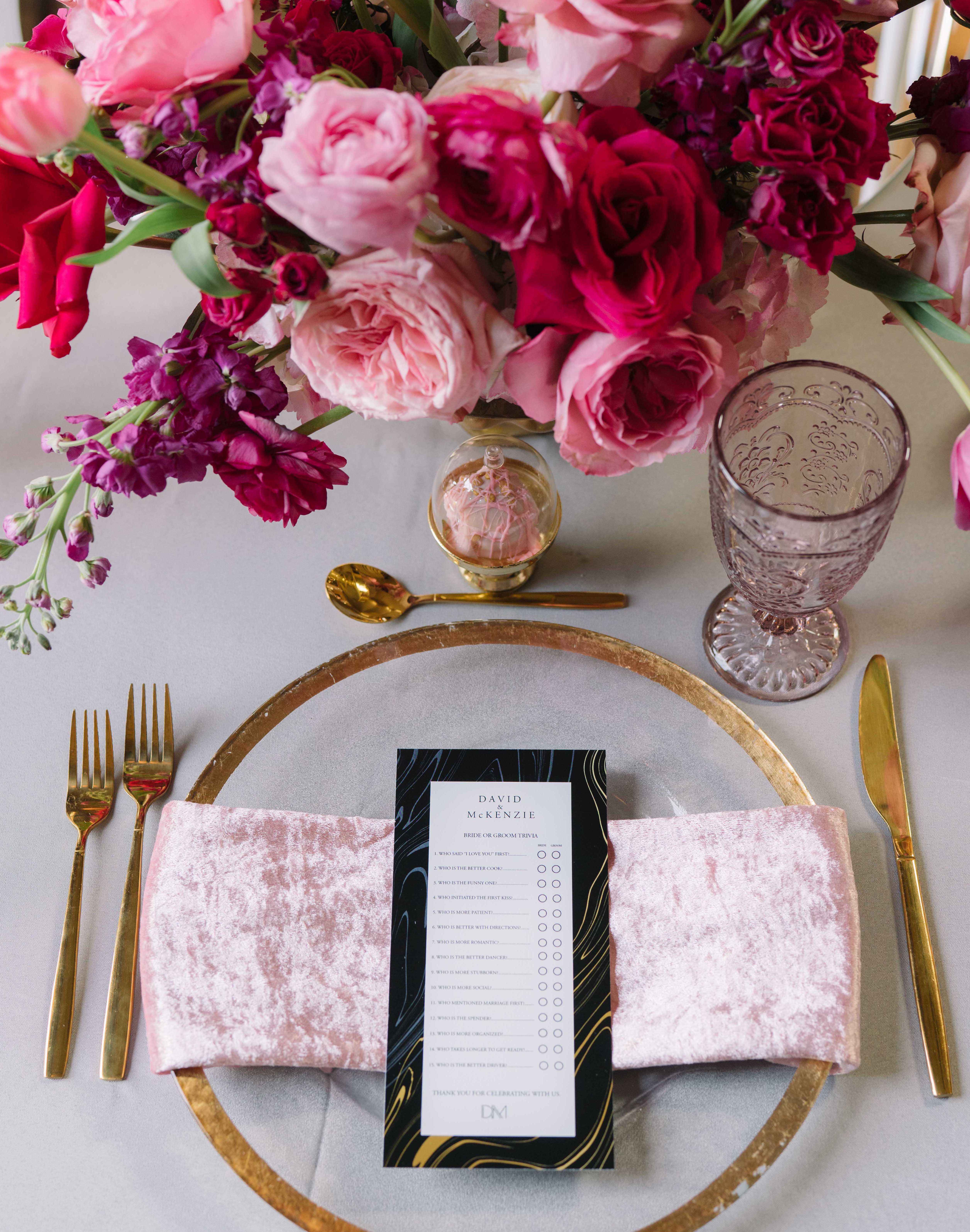 A wedding table setting with bright pink flowers and a velvet napkin for a Summer Wedding With a Vibrant Palette of Pink.