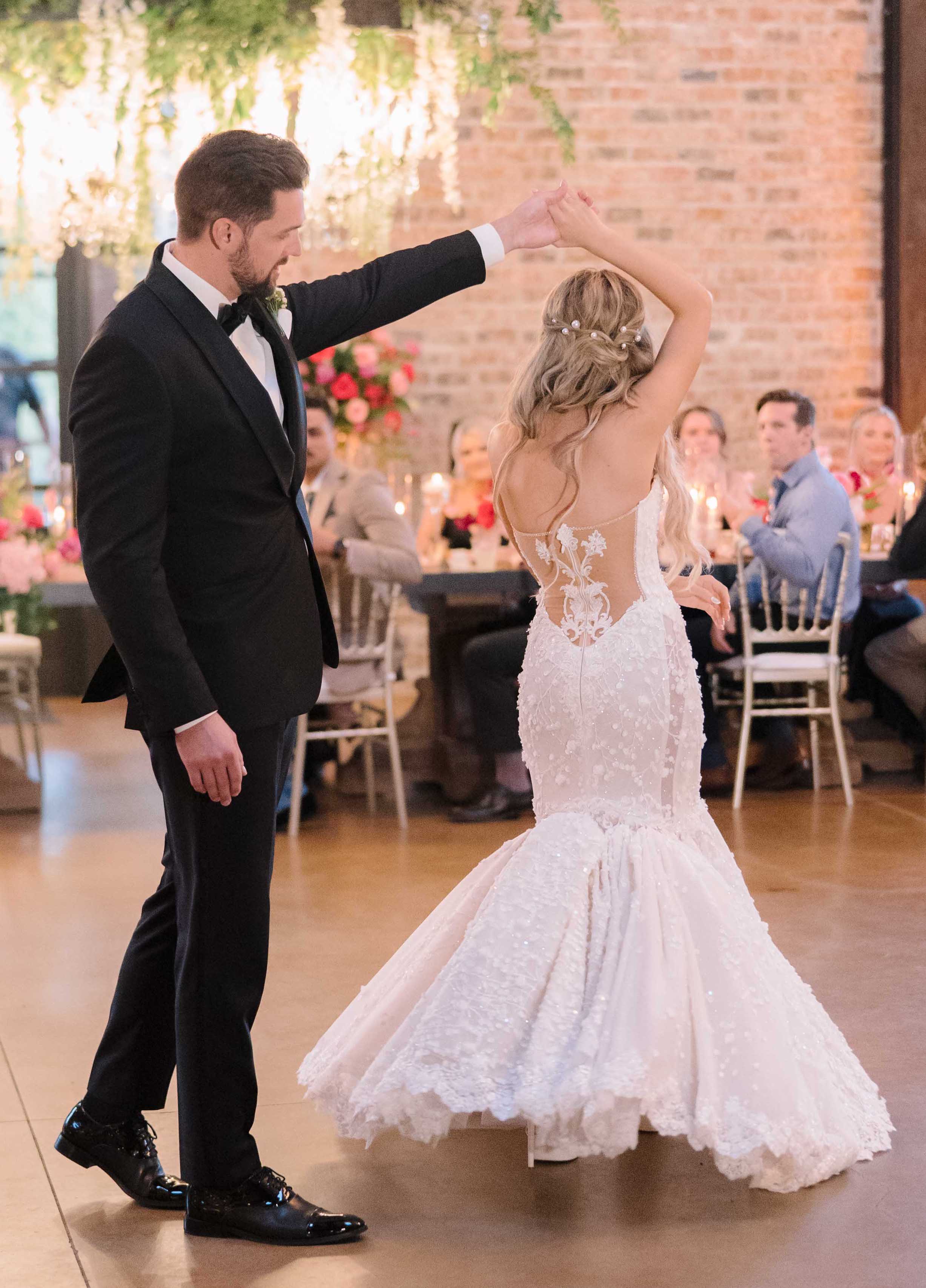 A groom twirls his bride on the dance floor during their wedding reception in Conroe, TX.