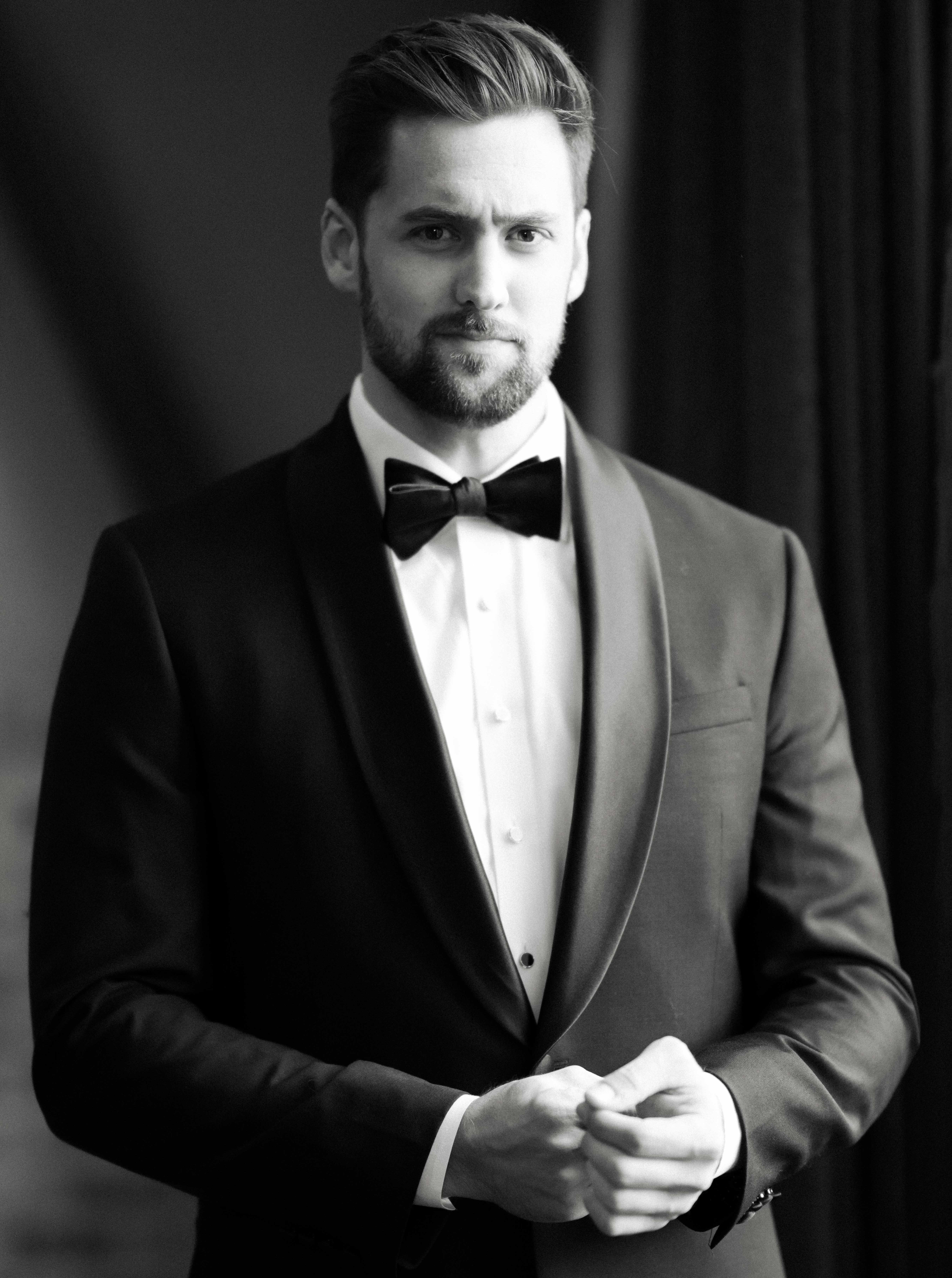 A black and white photo of a groom in his tuxedo before his wedding.