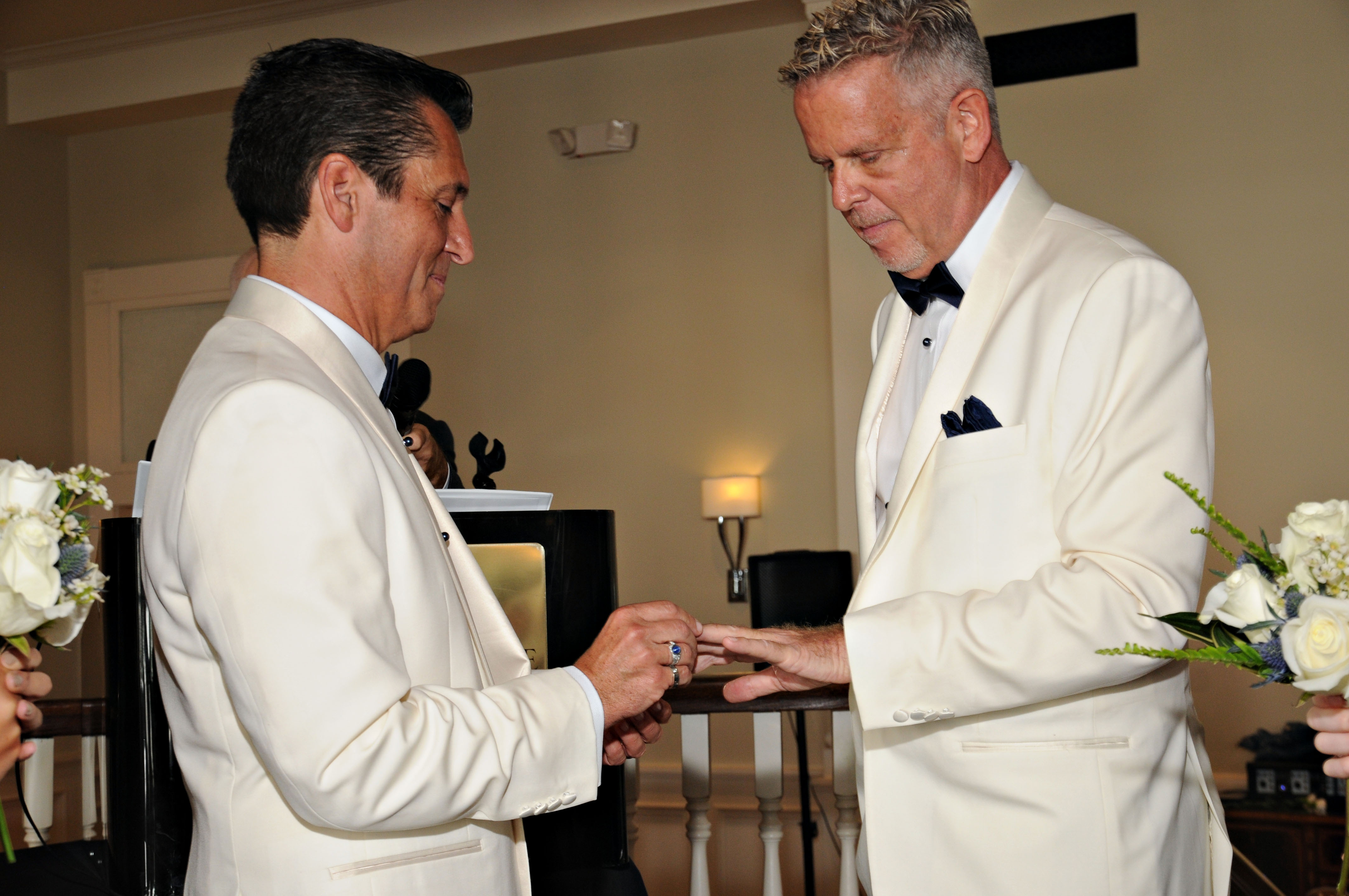 A groom and groom exchange wedding bands at their classic ceremony at The Tremont House Hotel in Galveston, TX.