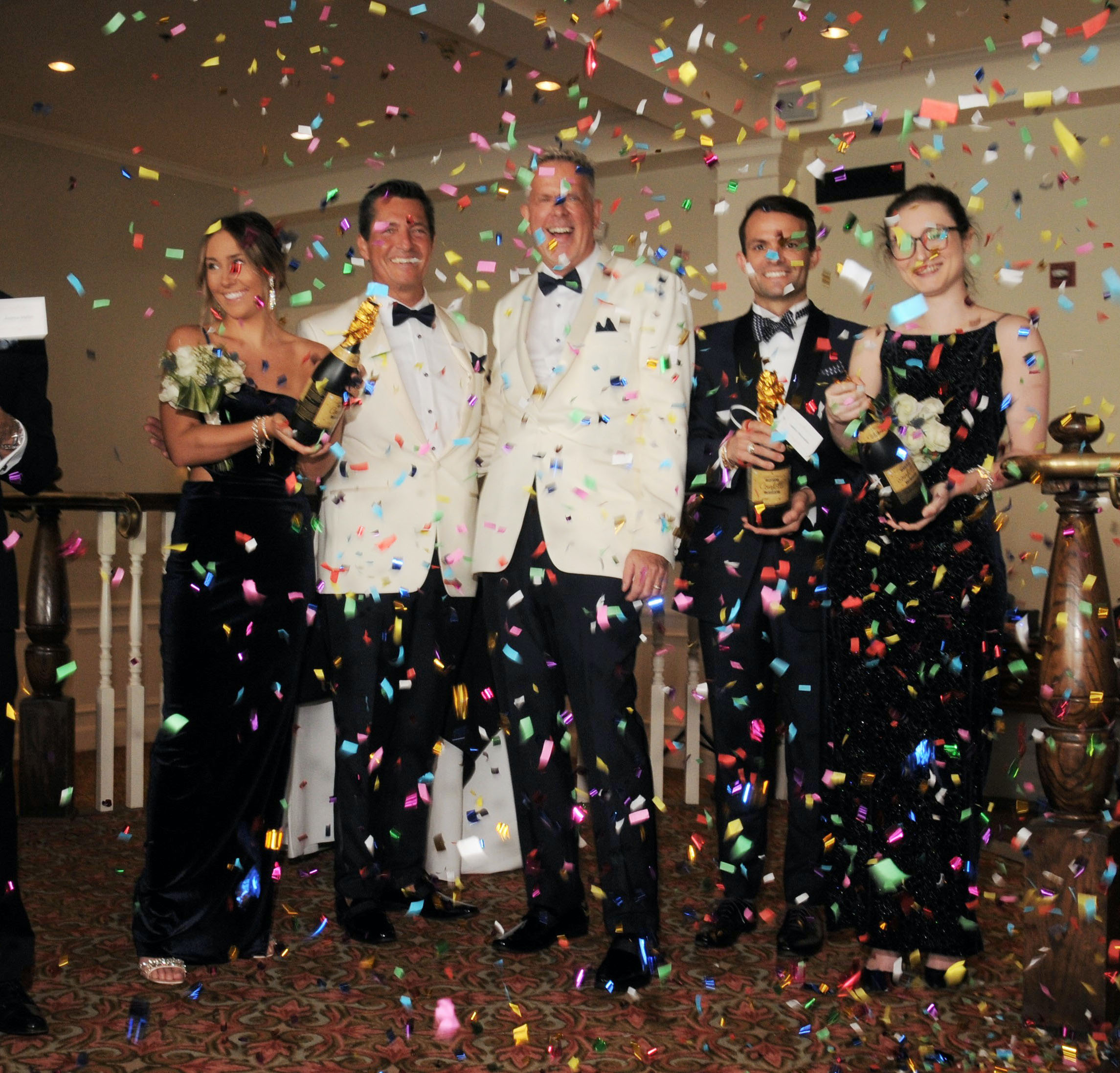 Colorful confetti explodes into the air with the groom and groom smiling behind at their wedding ceremony.