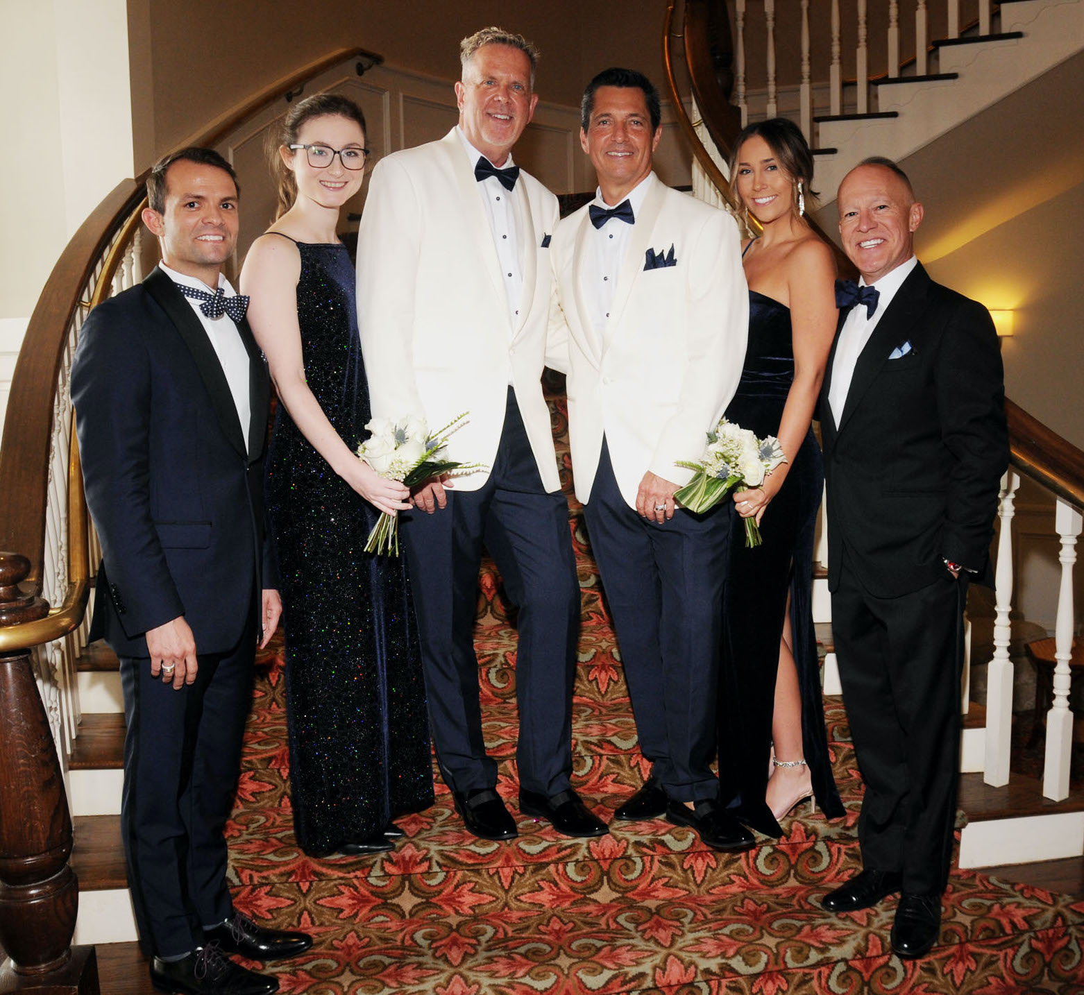 A groom and groom smile with their family members at their wedding ceremony in Galveston, TX.