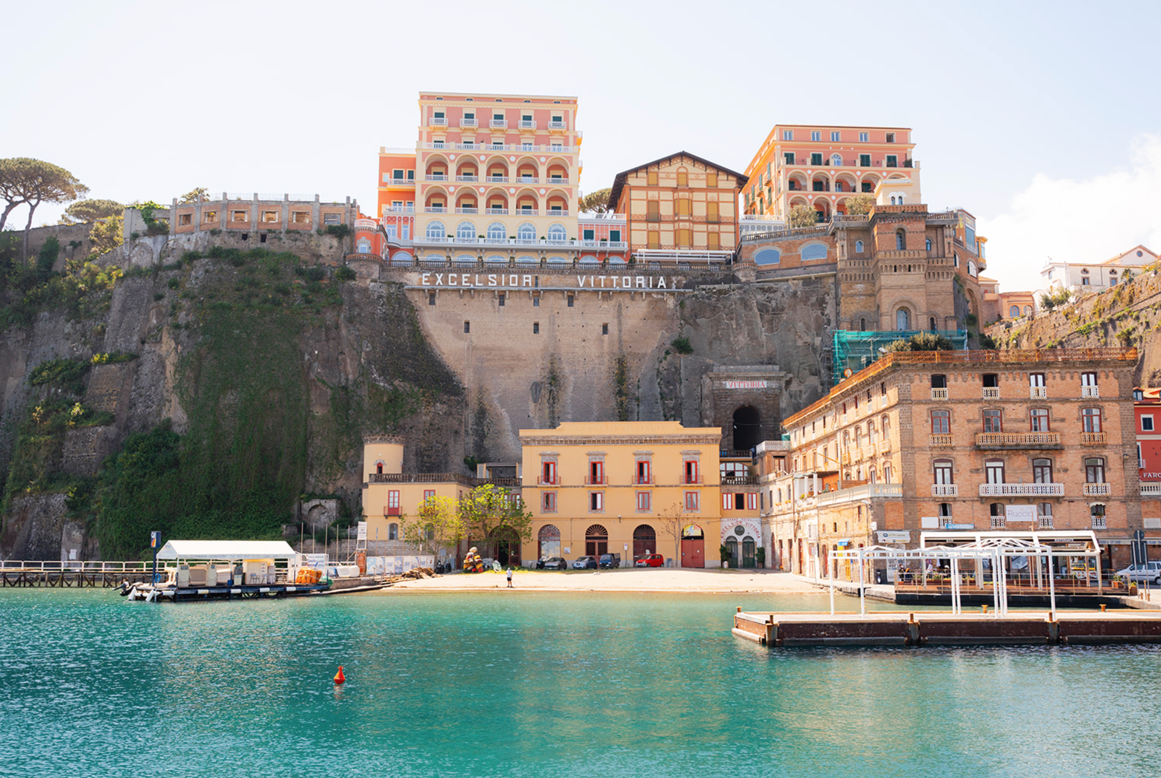 A shoreline on the Amalfi Coast with bright colored buildings and turquoise waters.