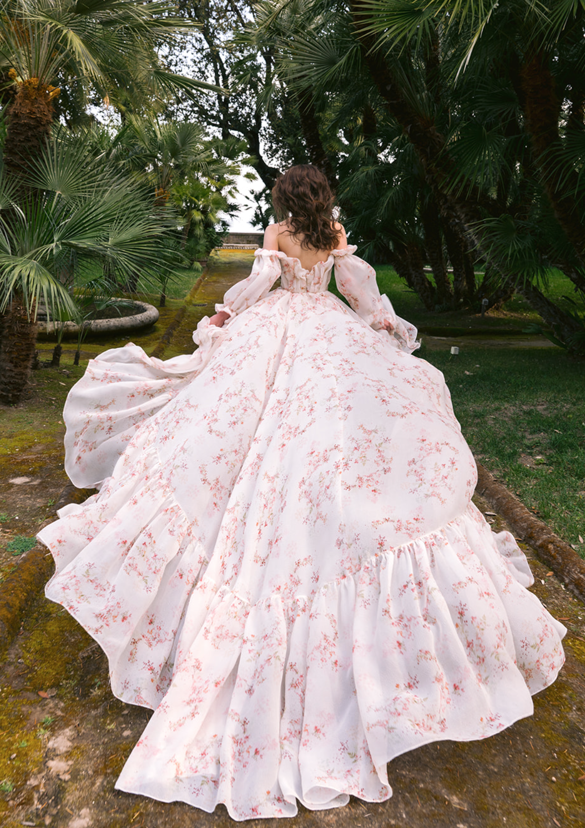 A bride runs outside in a flowy off-the-shoulder Monique Lhuillier gown with a dainty pink flower pattern designed all over the dress.