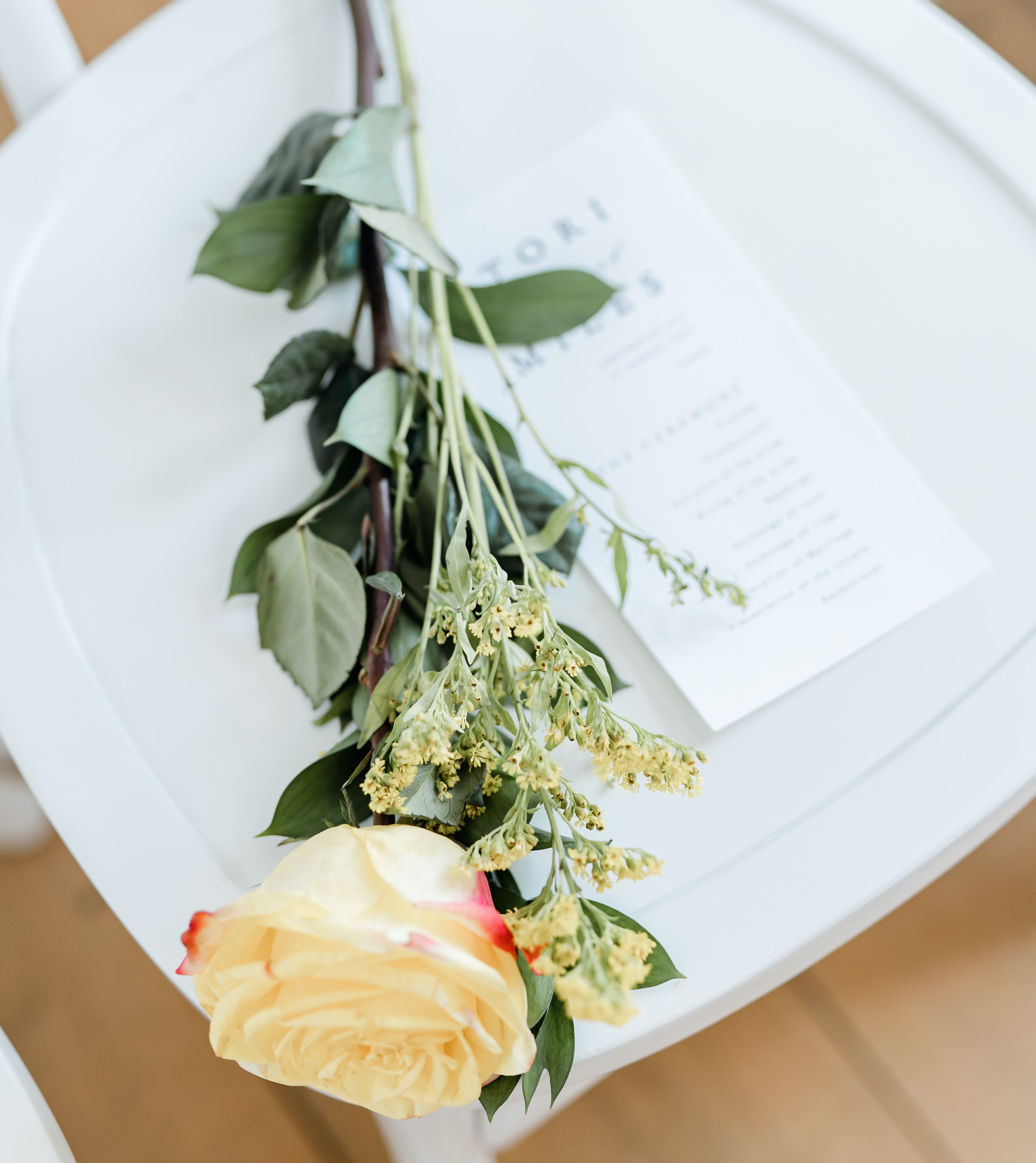 A single yellow rose is paired with some yellow flowers on a chair at a wedding ceremony in Montgomery, Texas for an elegant summer wedding.